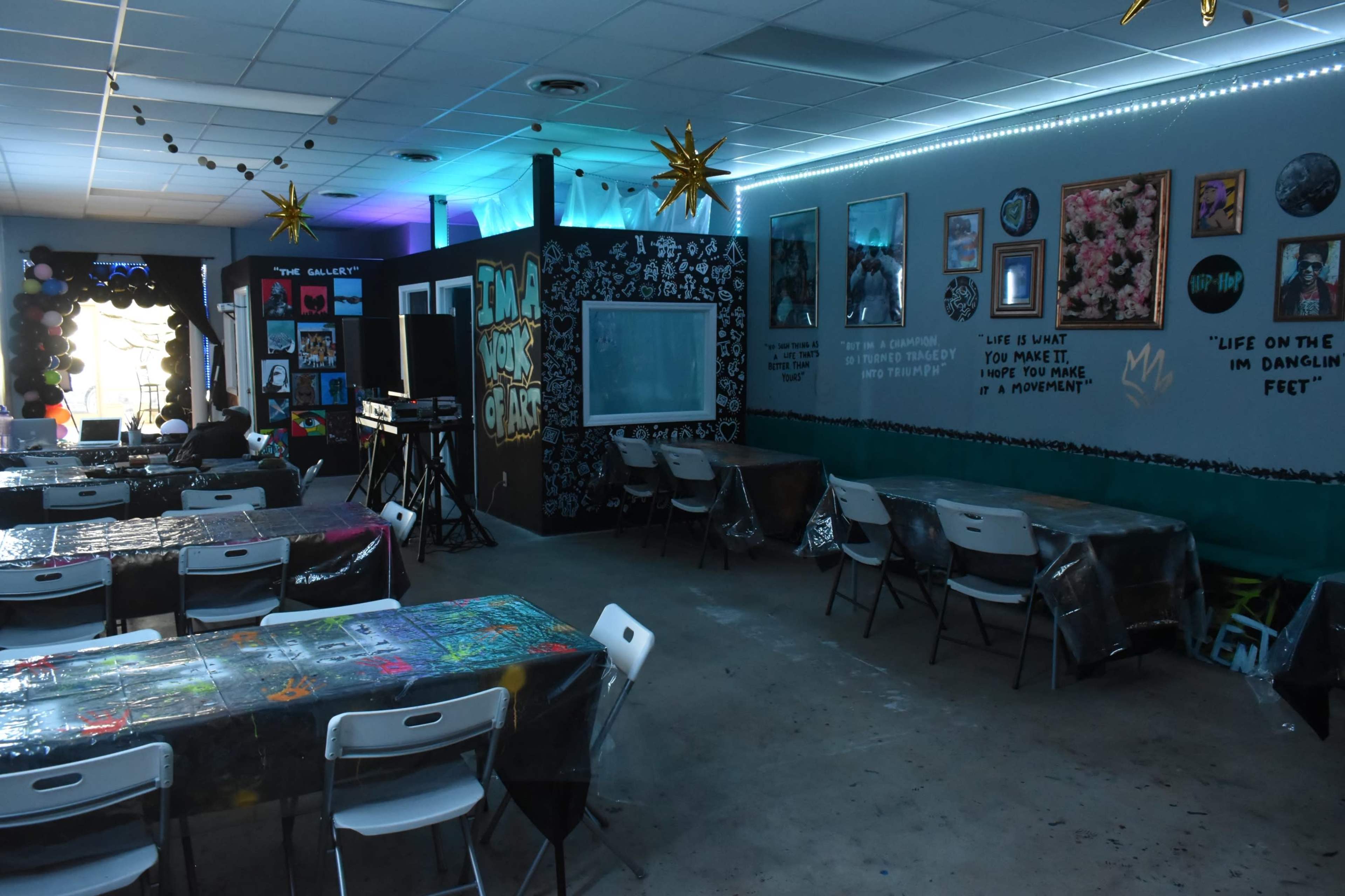 A colorful classroom setting with decorated tables, inspirational quotes on the walls, and various artworks displayed.