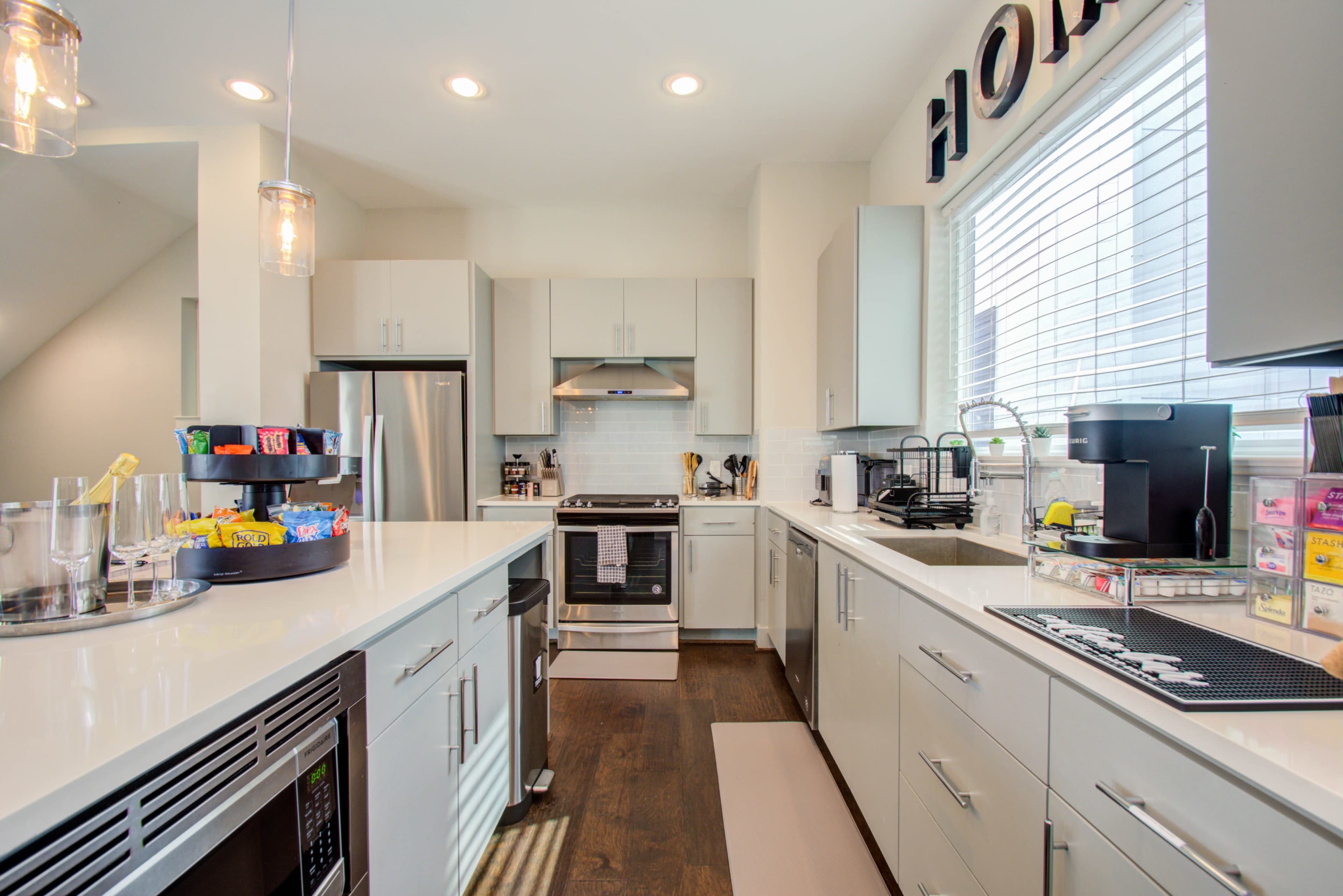 A modern kitchen features stainless steel appliances, white cabinets, and a central island with a circular tray of snacks.