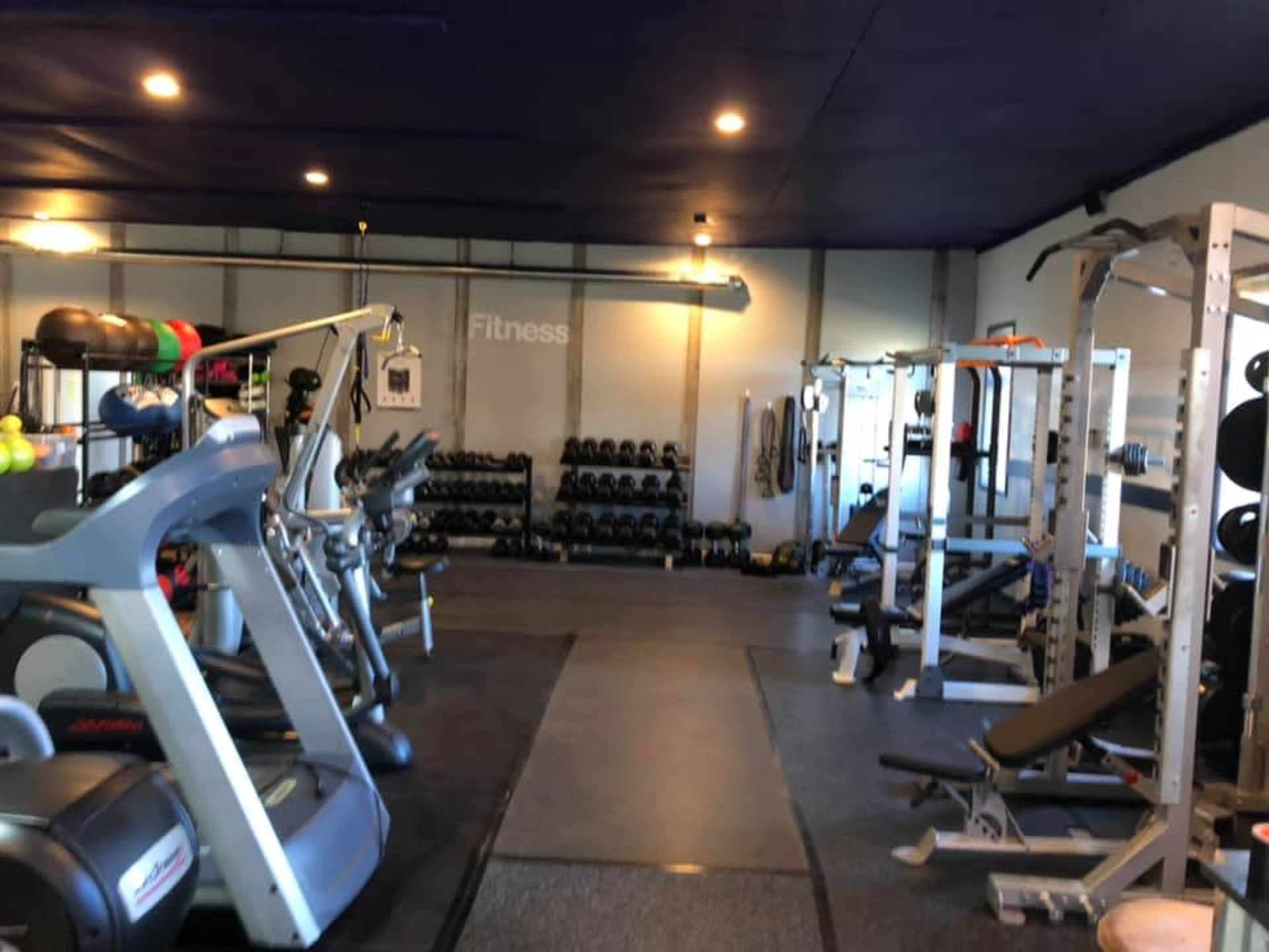 A fitness gym equipped with exercise machines, free weights, and cardio equipment arranged in a spacious layout.
