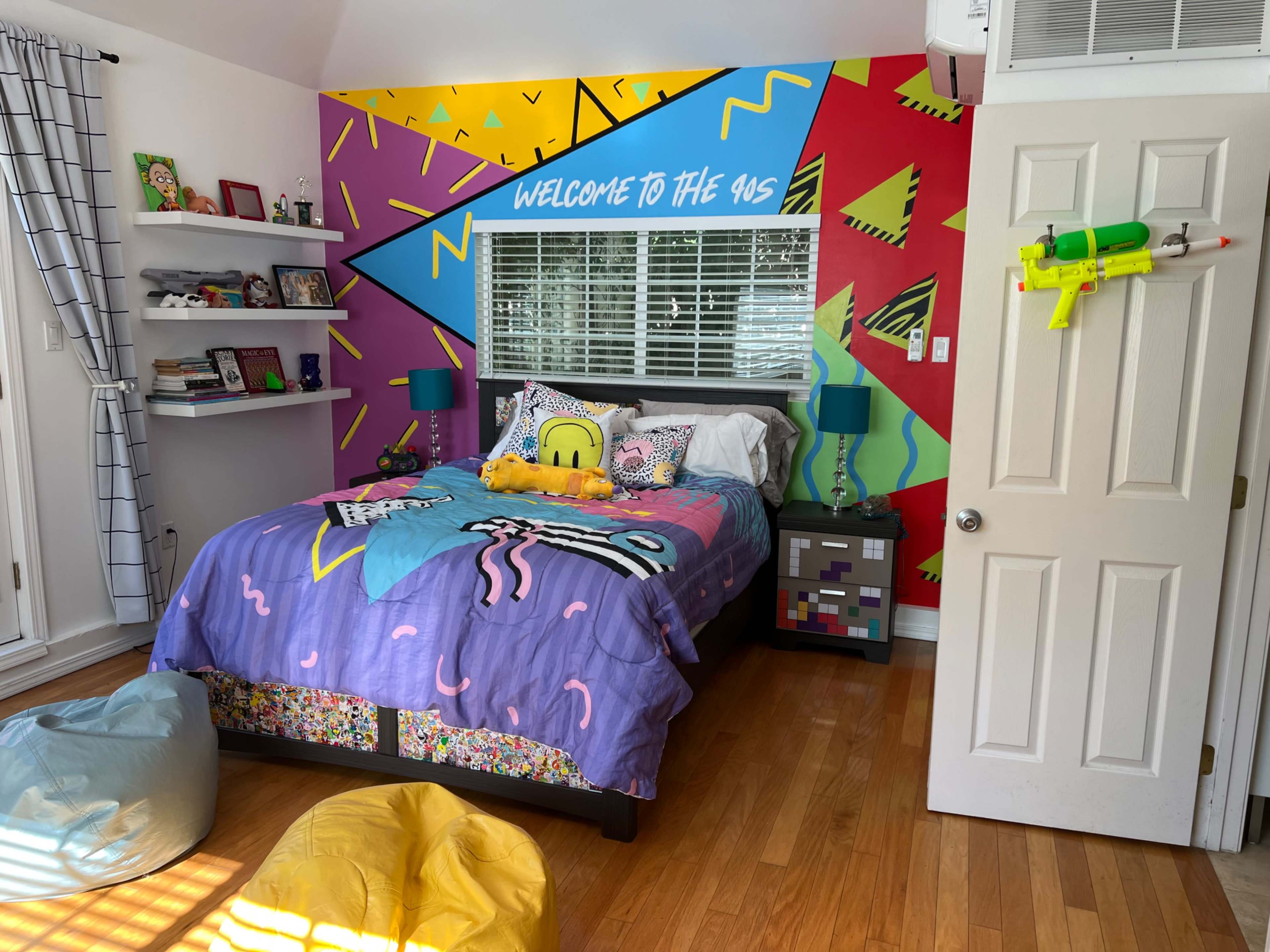 A brightly decorated bedroom featuring a patterned bedspread, a colorful mural on the wall, and various playful accessories.