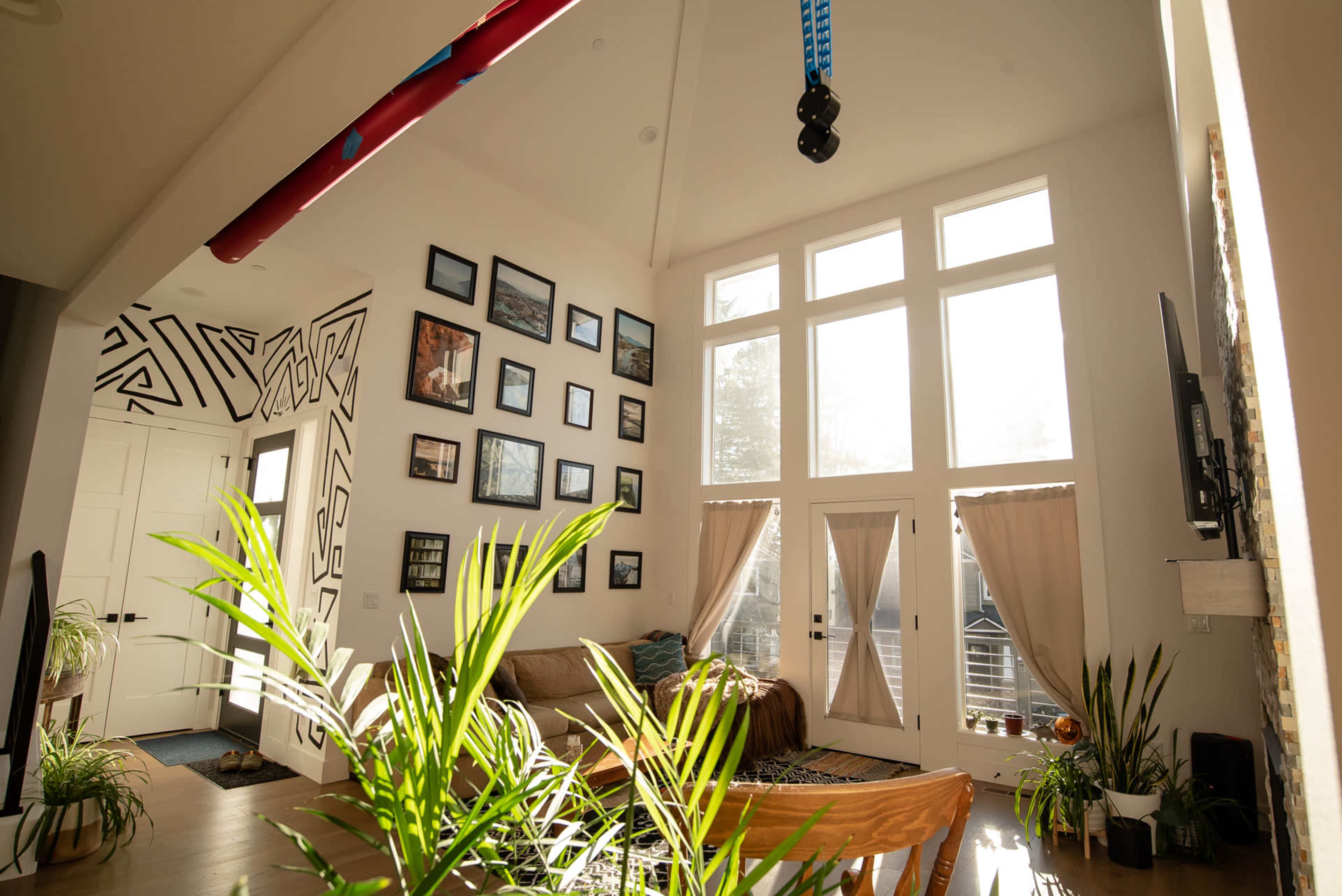 A bright living room with large windows, a sofa, and various framed pictures on the wall.