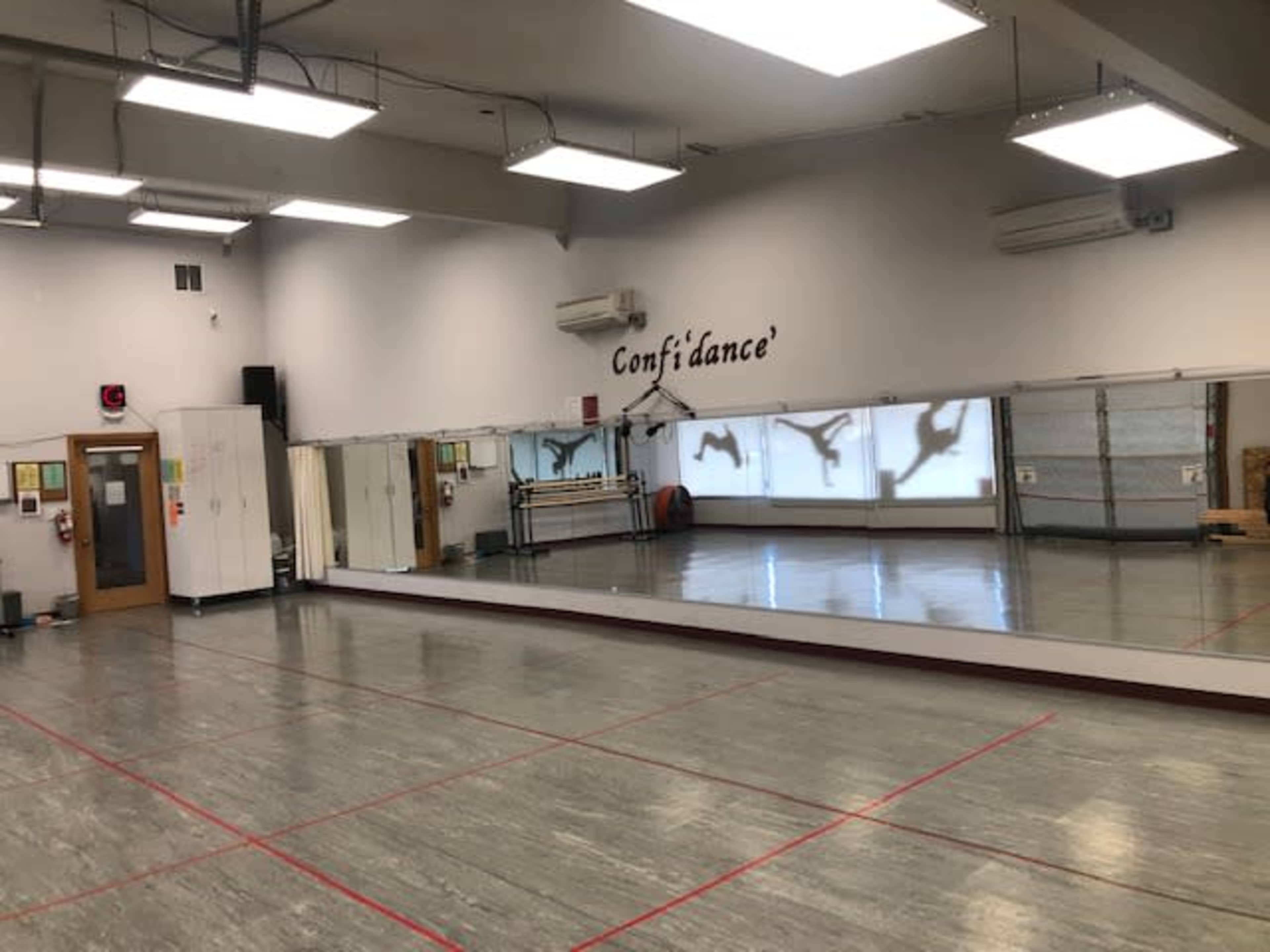 A dance studio with a large mirror along one wall and a motivational phrase written above it.