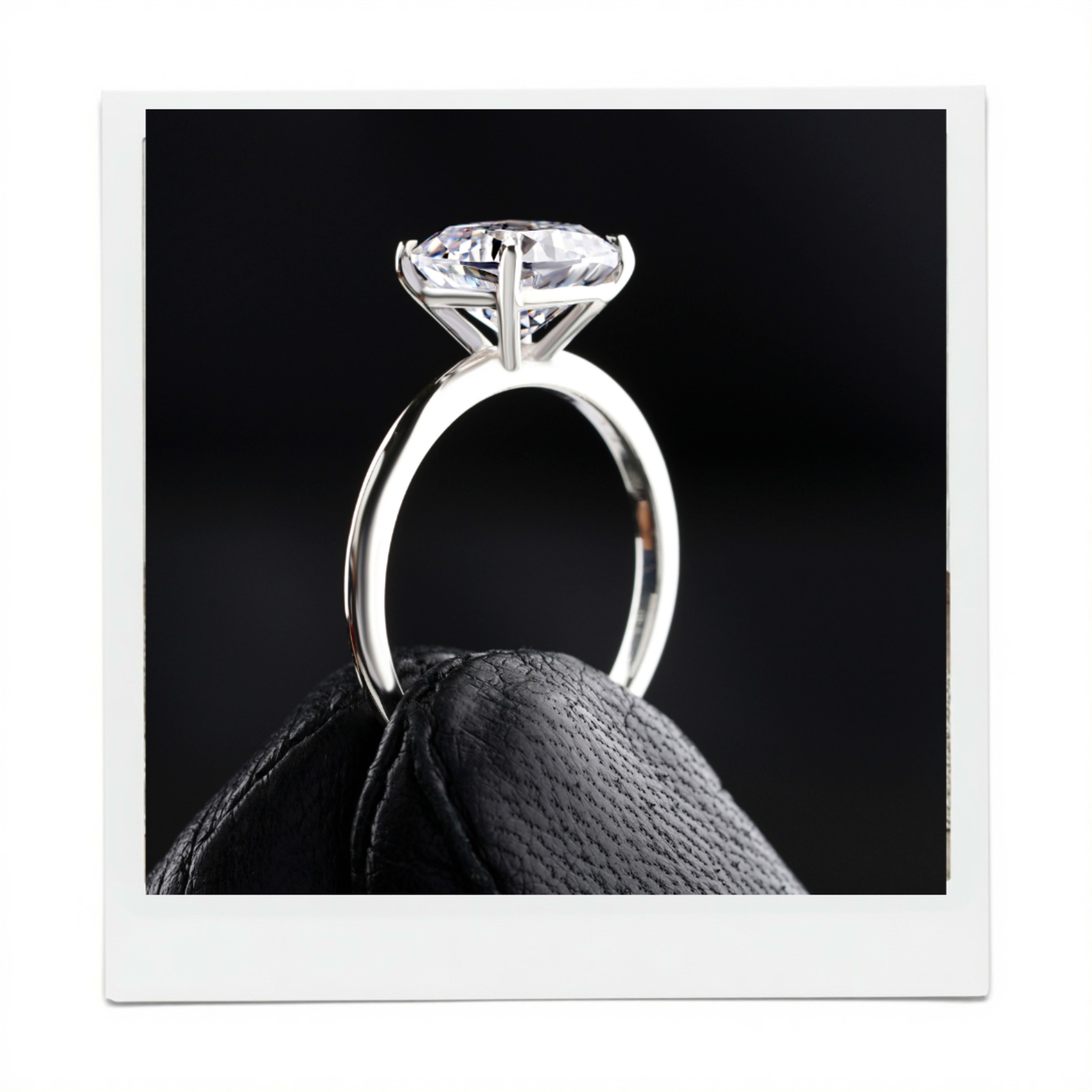 A close-up photograph of a diamond engagement ring displayed on a textured black surface.