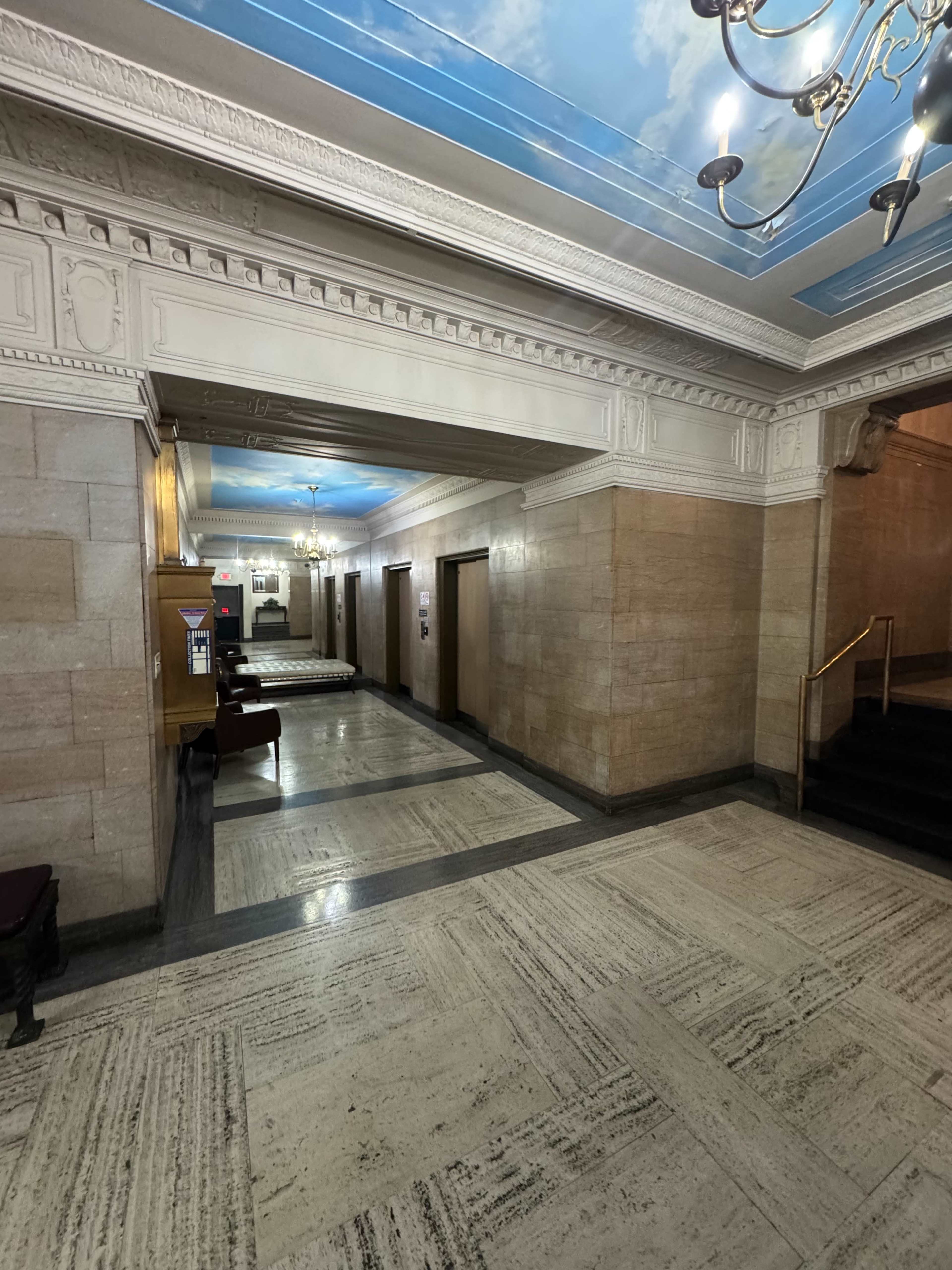 The image shows a corridor in a building featuring marble walls, a ceiling painted with clouds, and multiple doorways leading to unknown rooms.