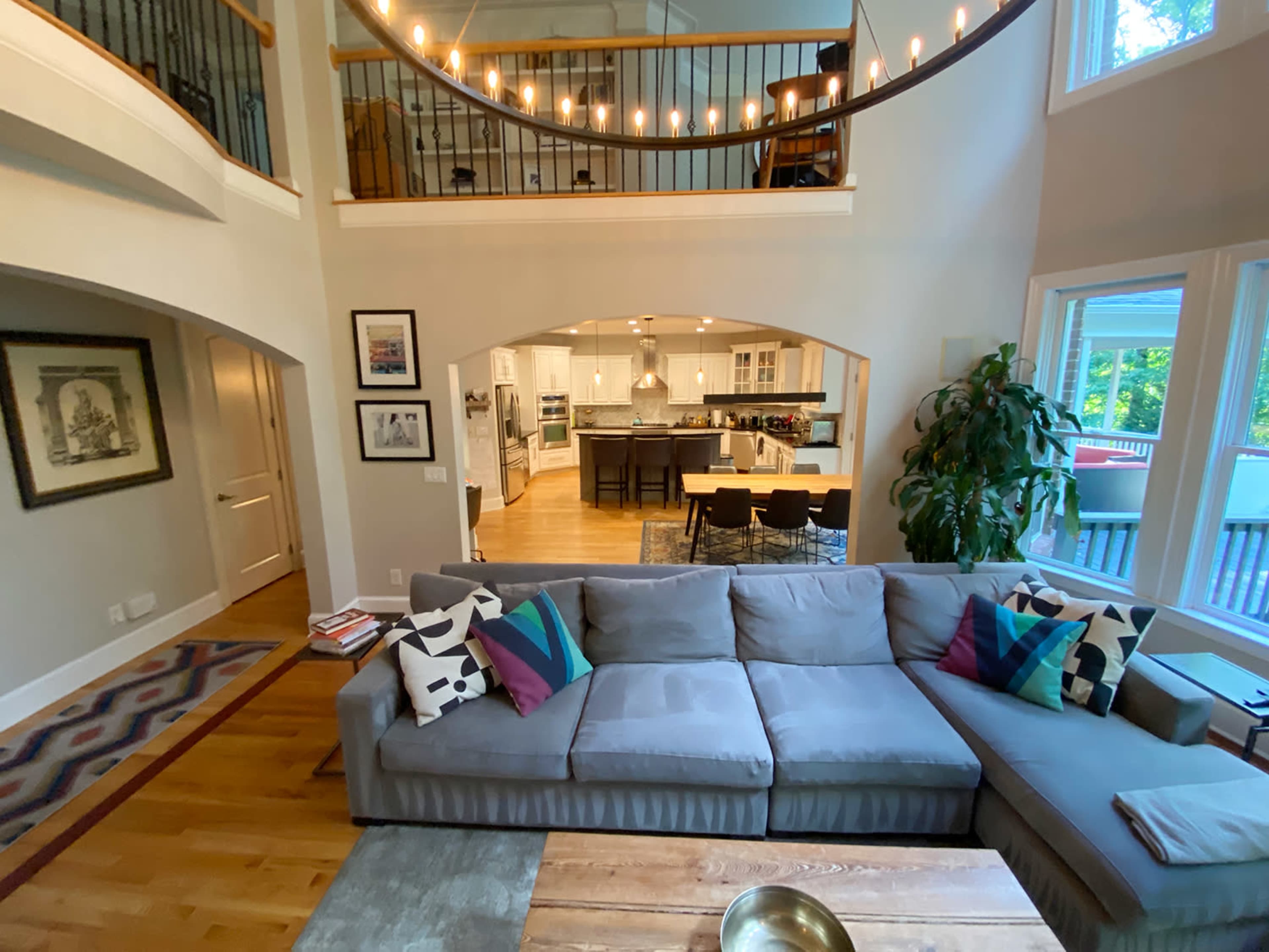 A spacious living area with a gray sectional sofa, wooden coffee table, and a view into an open kitchen with modern appliances.
