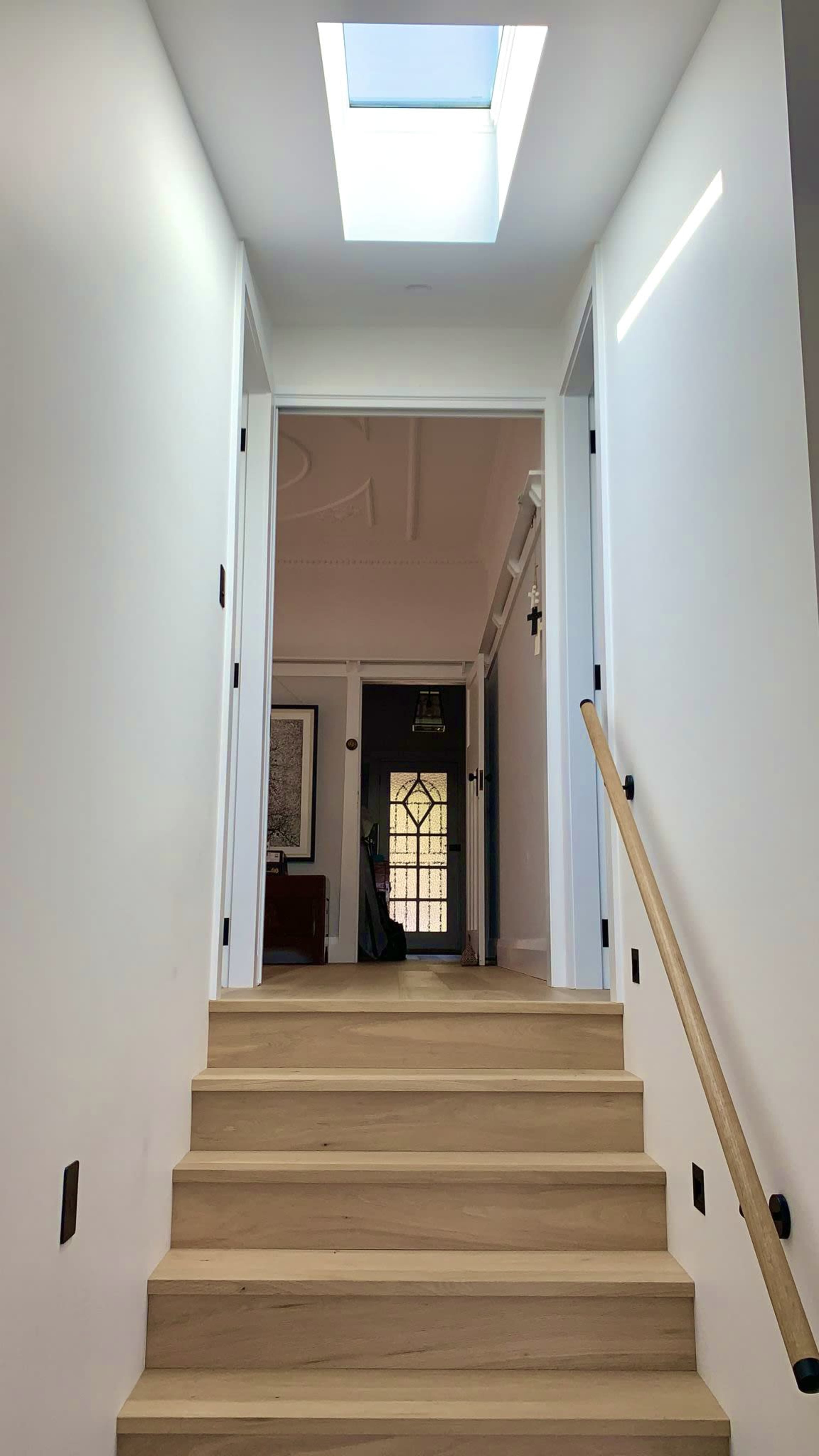 A staircase leads to a hallway with a skylight and doors on either side.