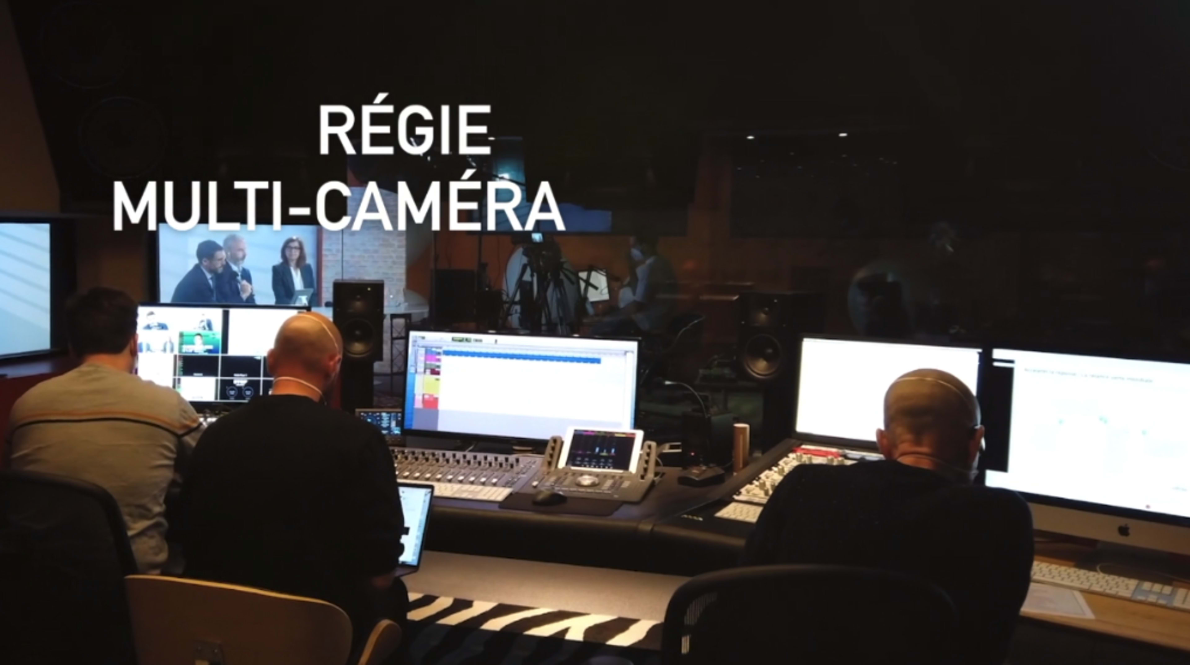 A multi-camera control room with several people working at computers and audio equipment.