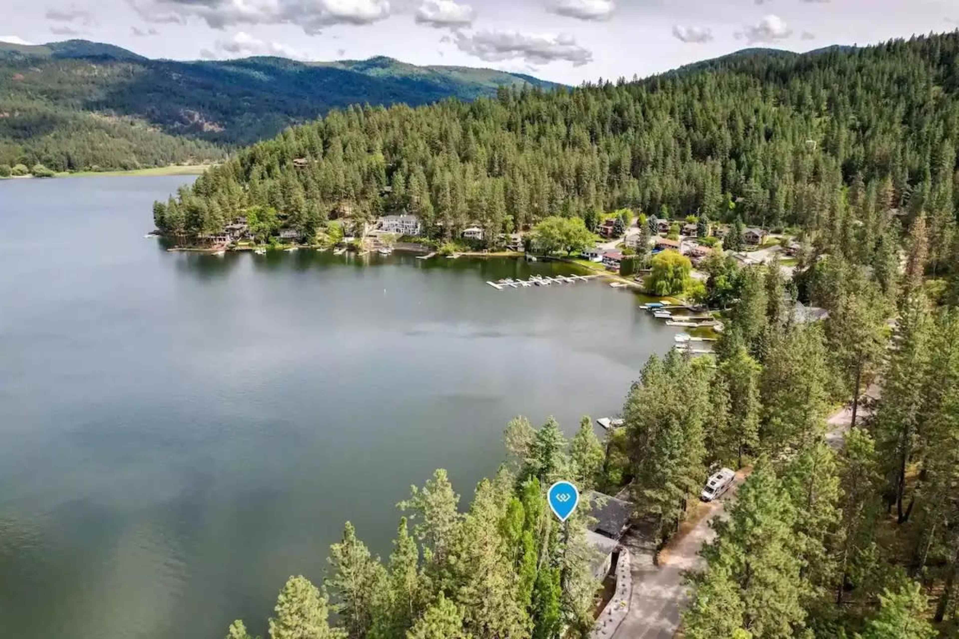 A scenic view of a lake surrounded by trees and residential areas with boats parked along the shore.