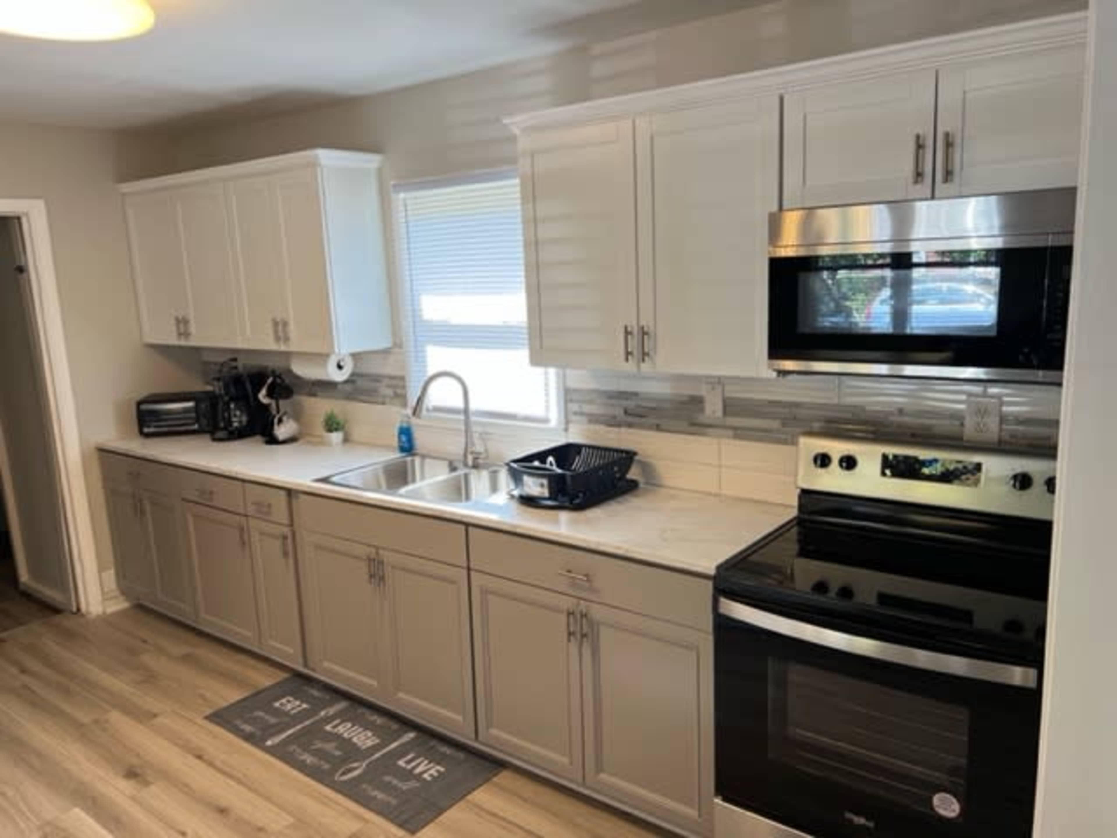 A modern kitchen featuring white cabinets, stainless steel appliances, and a window above the sink.
