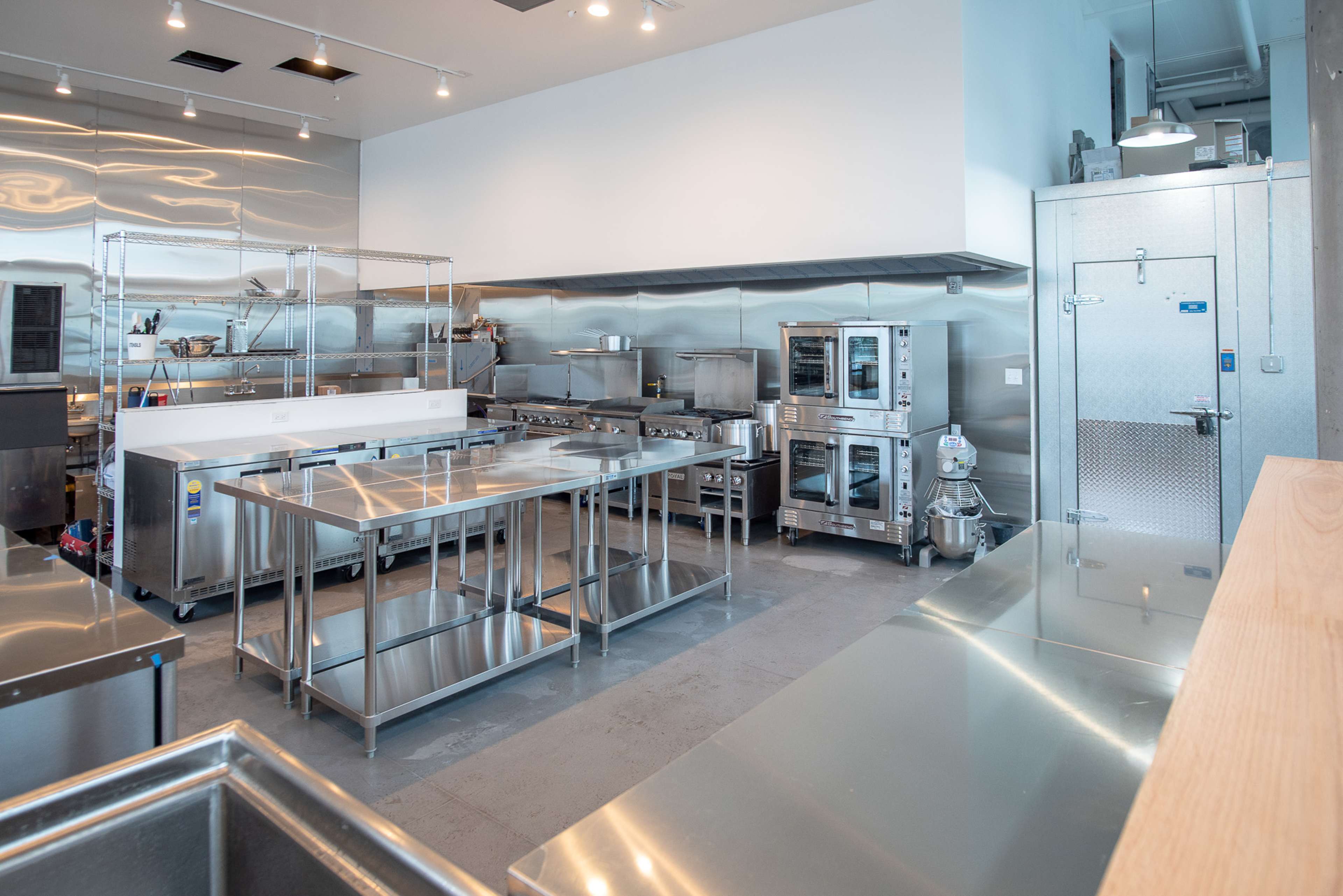 A modern commercial kitchen with stainless steel countertops, industrial appliances, and an organized layout.