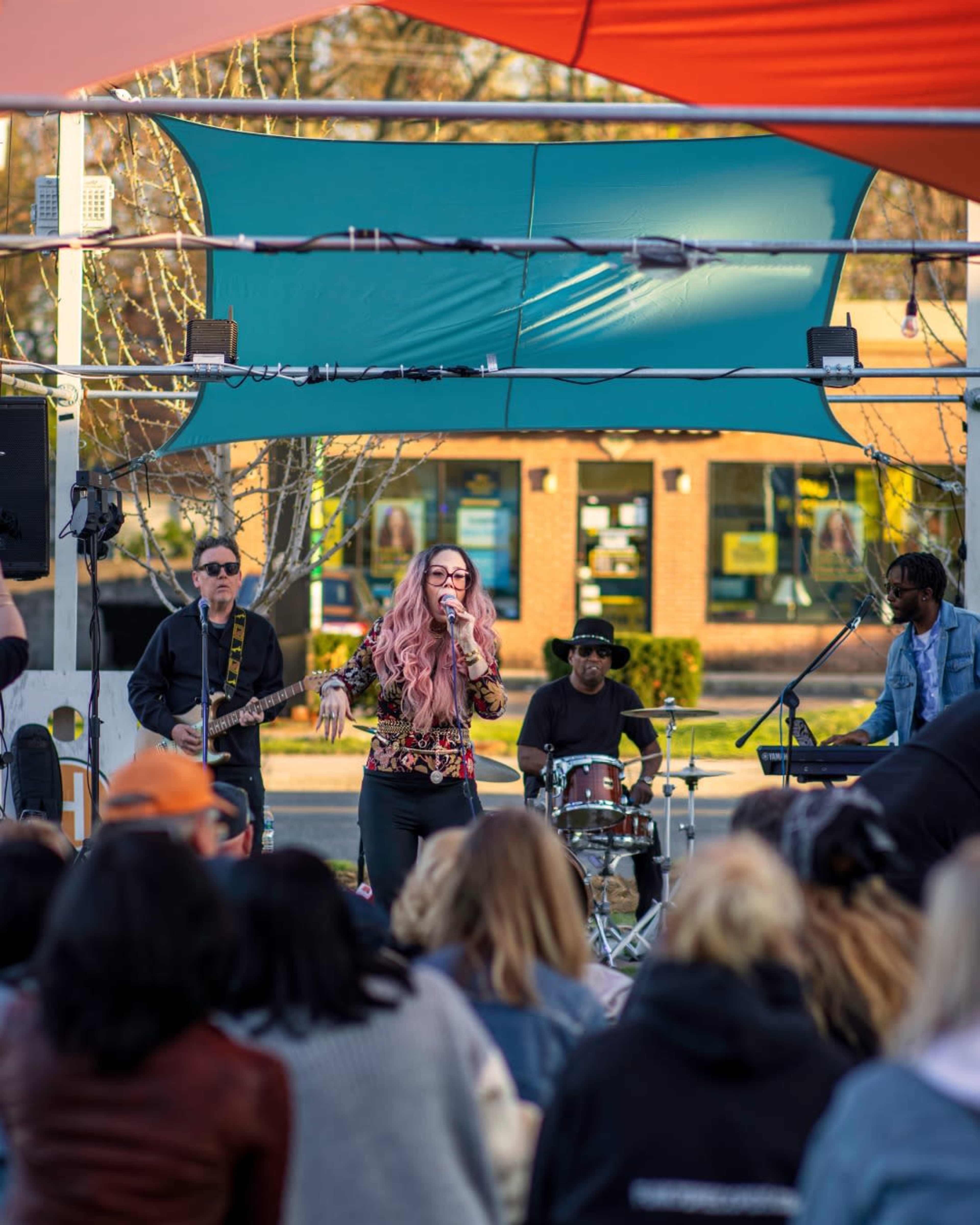 A singer performs on stage in front of an audience while a band plays behind her.