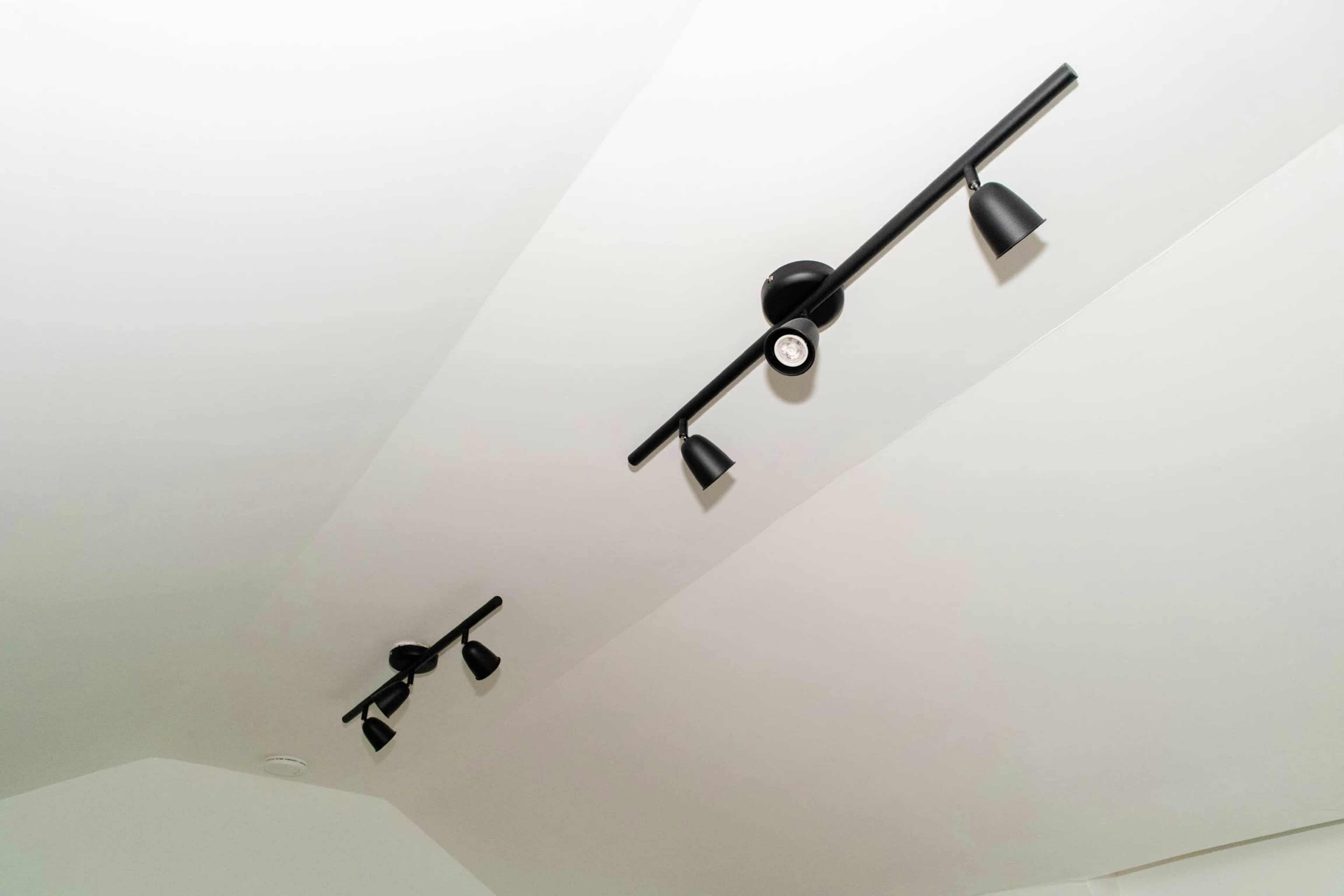 Two black track lighting fixtures mounted on a white ceiling.