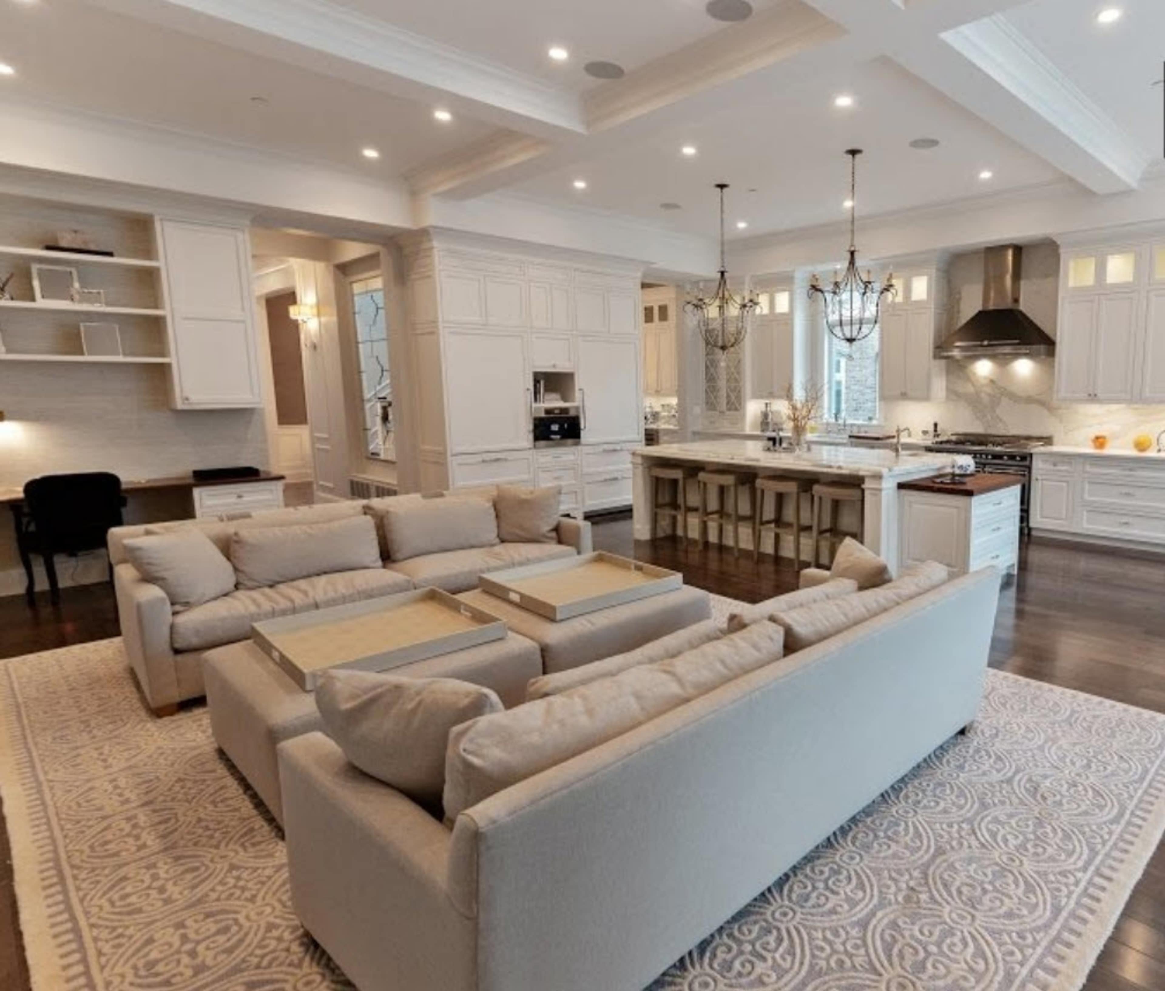 A spacious kitchen and living area with a large sectional sofa, an island with bar stools, and white cabinetry.