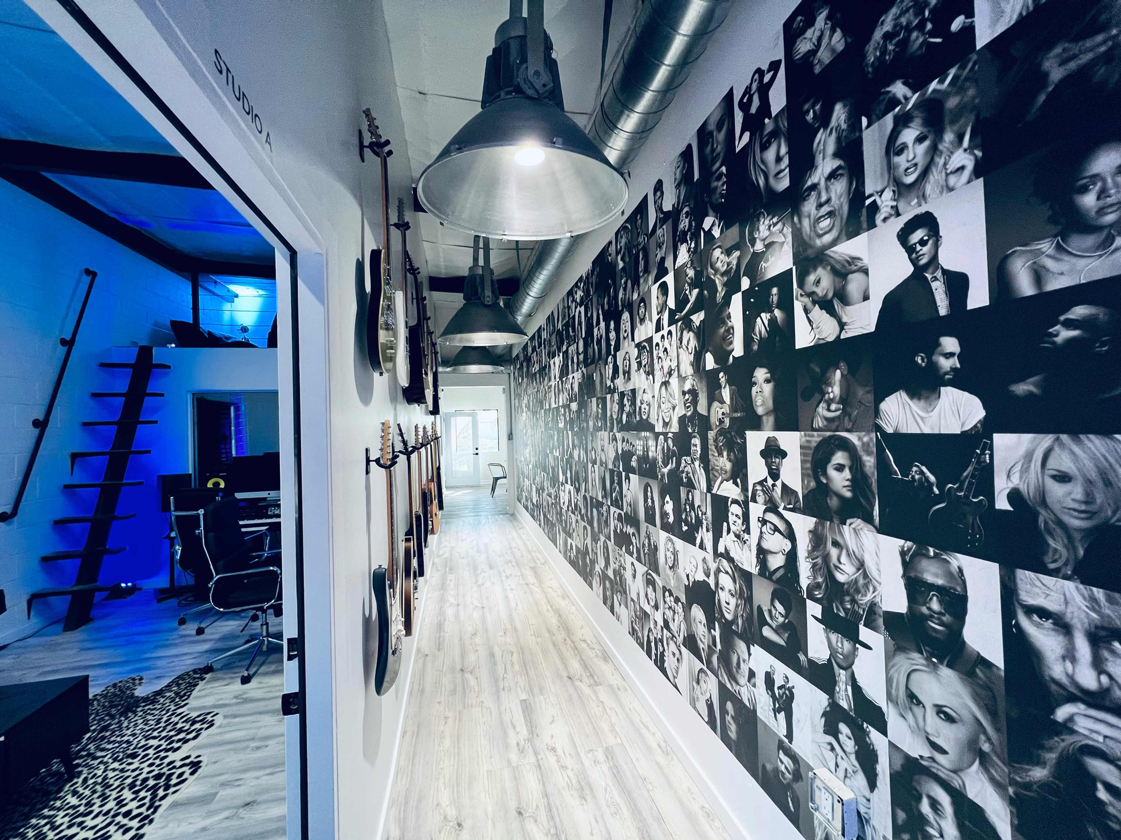 A long hallway features a wall covered with black-and-white portraits, with studios and guitars visible in the background.