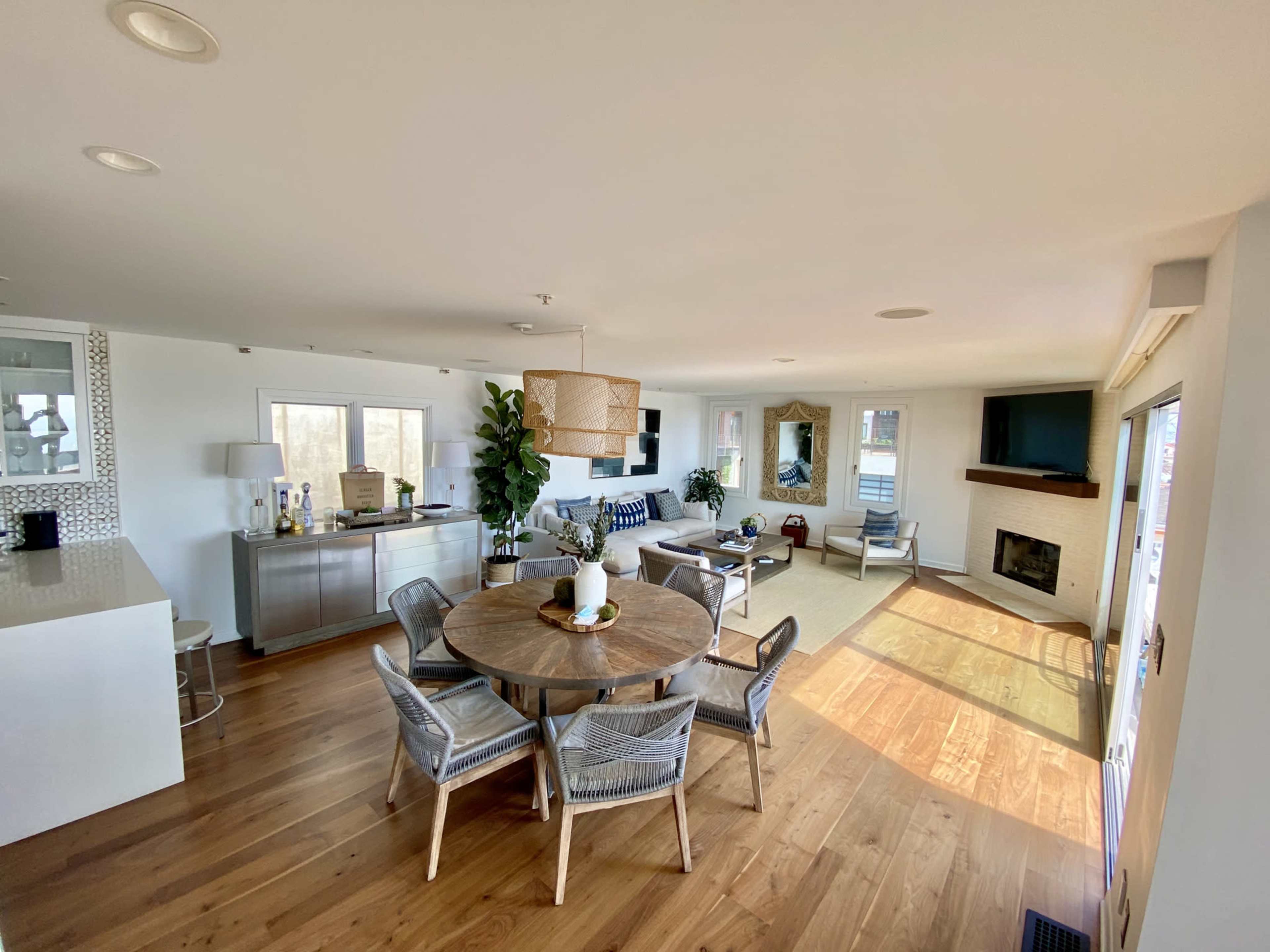 A modern open-concept living space with a dining area, seating arrangement, and a fireplace.