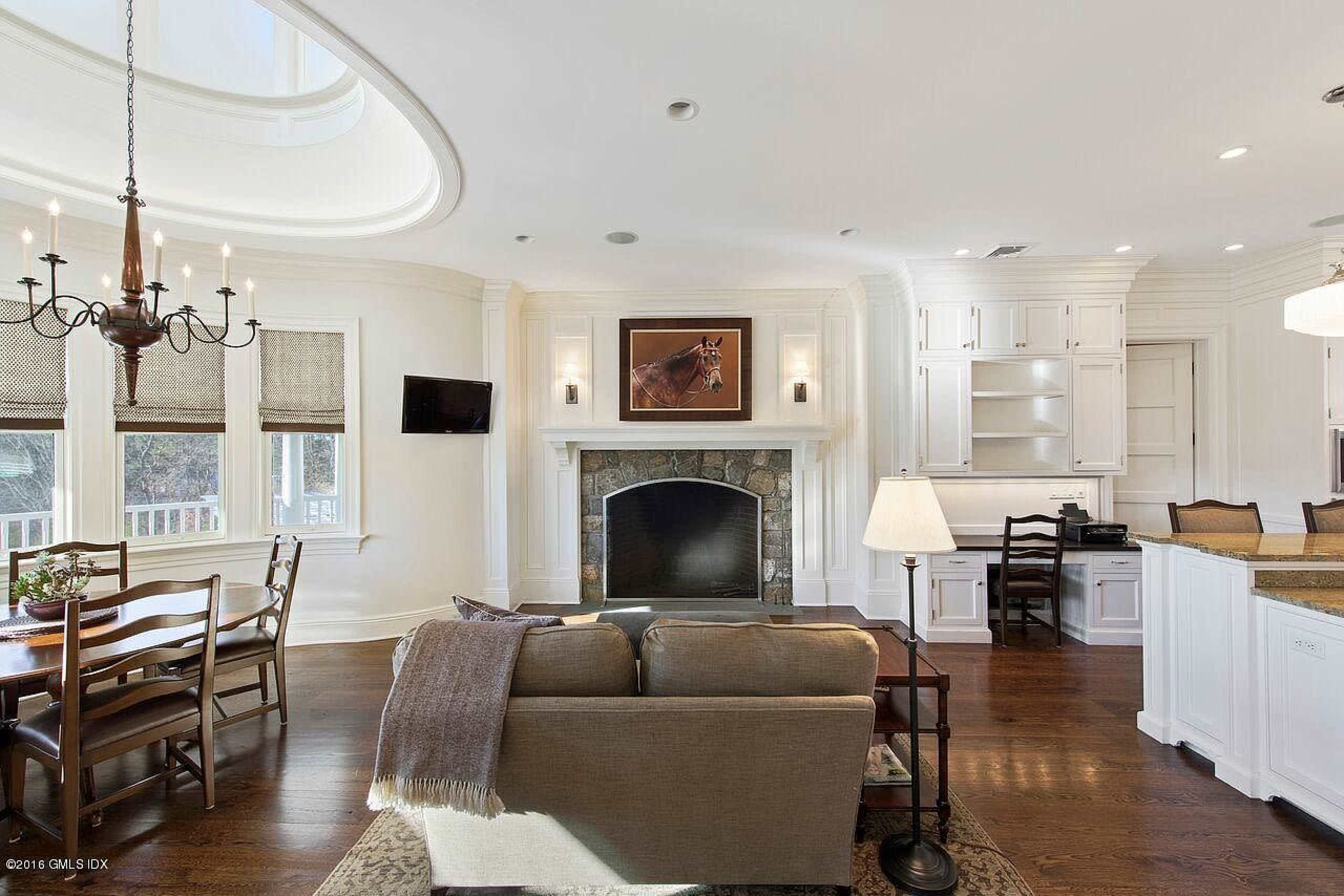 The image shows a modern, open-concept living space featuring a dining area, a cozy seating arrangement, a fireplace with a stone surround, and a well-equipped kitchen.