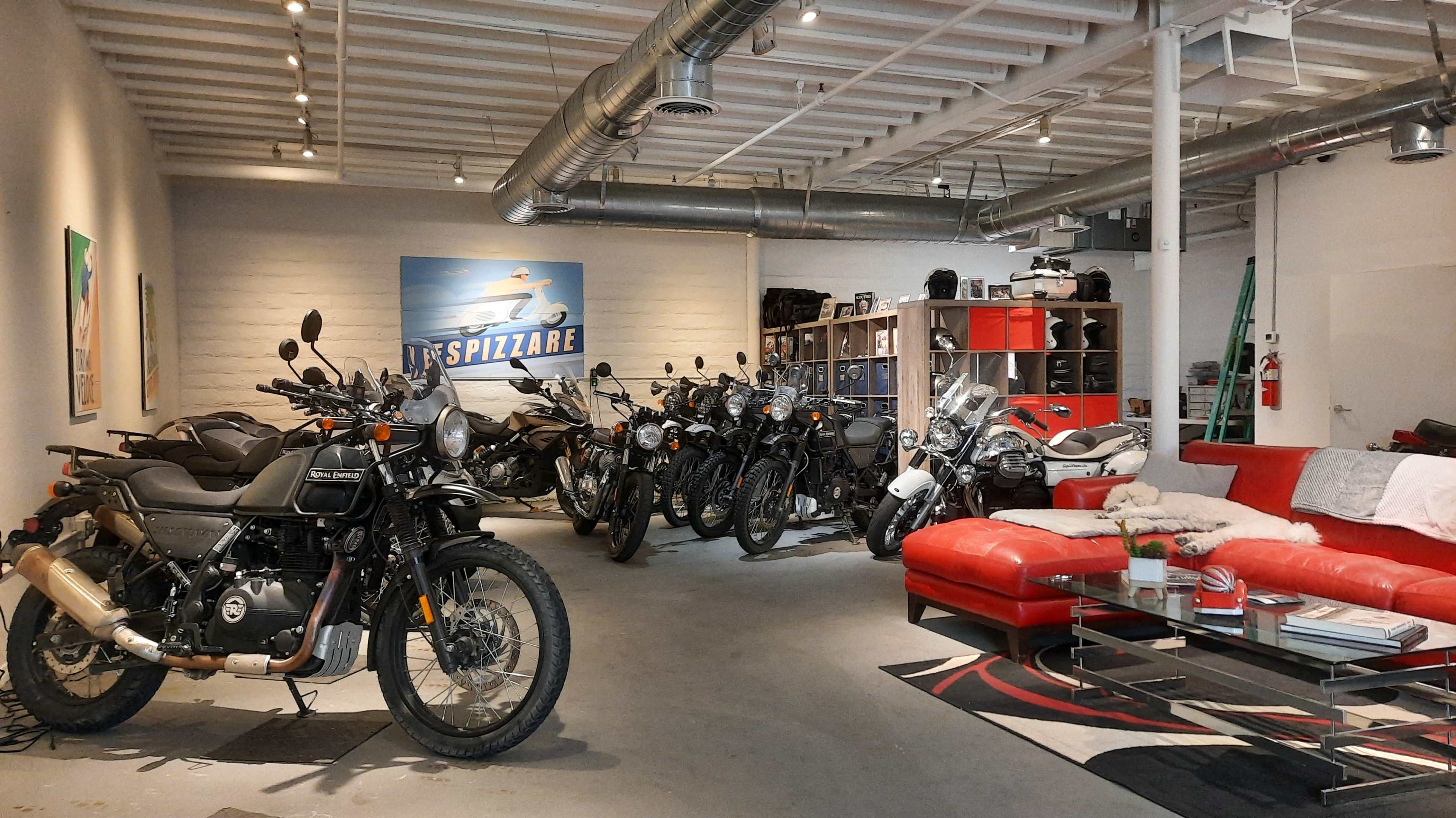 A motorcycle showroom featuring several bikes arranged alongside a modern red sofa and coffee table.