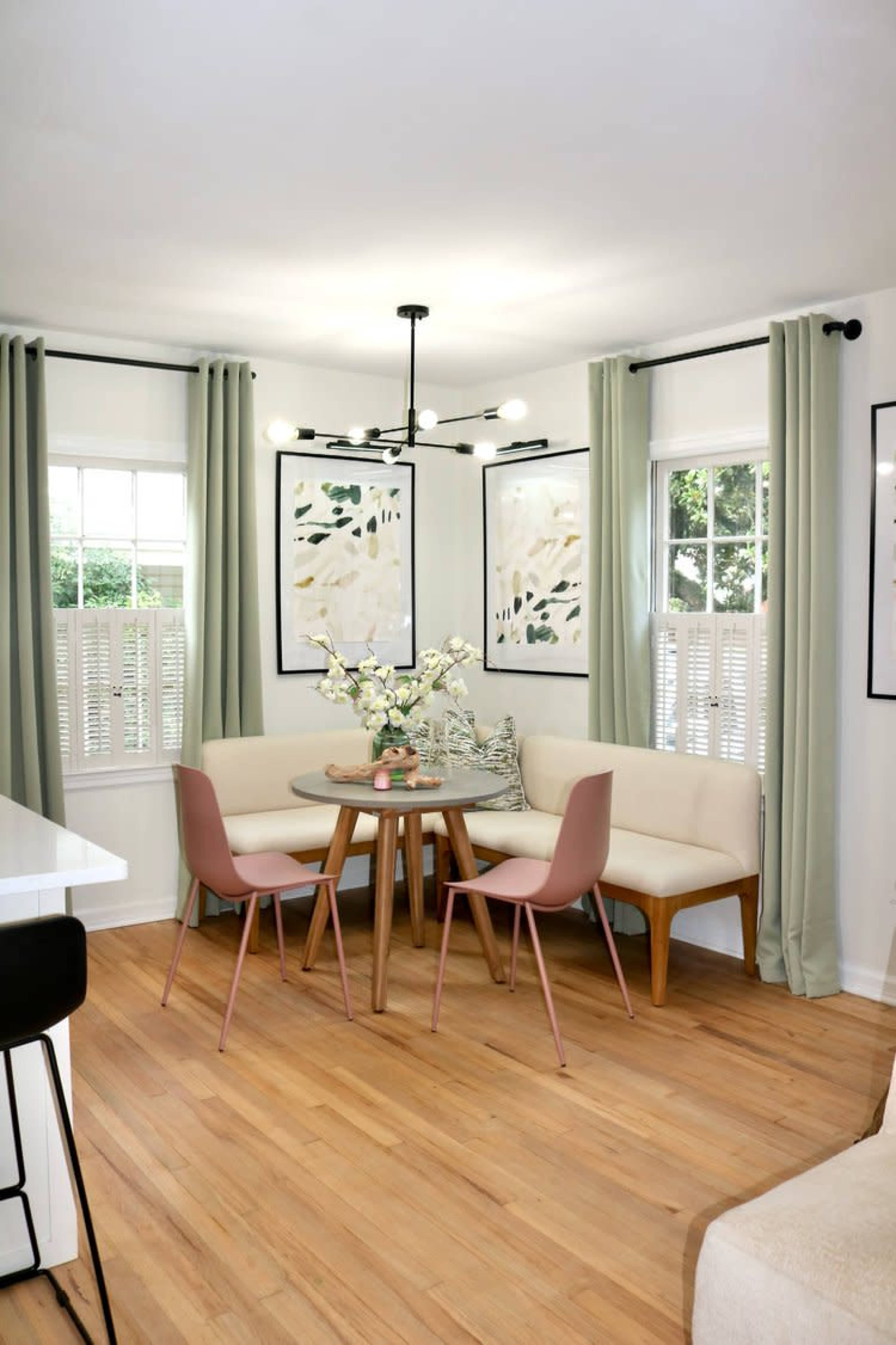 A cozy dining area features a round table surrounded by four chairs, with a banquette seating arrangement and decorative artwork on the walls.