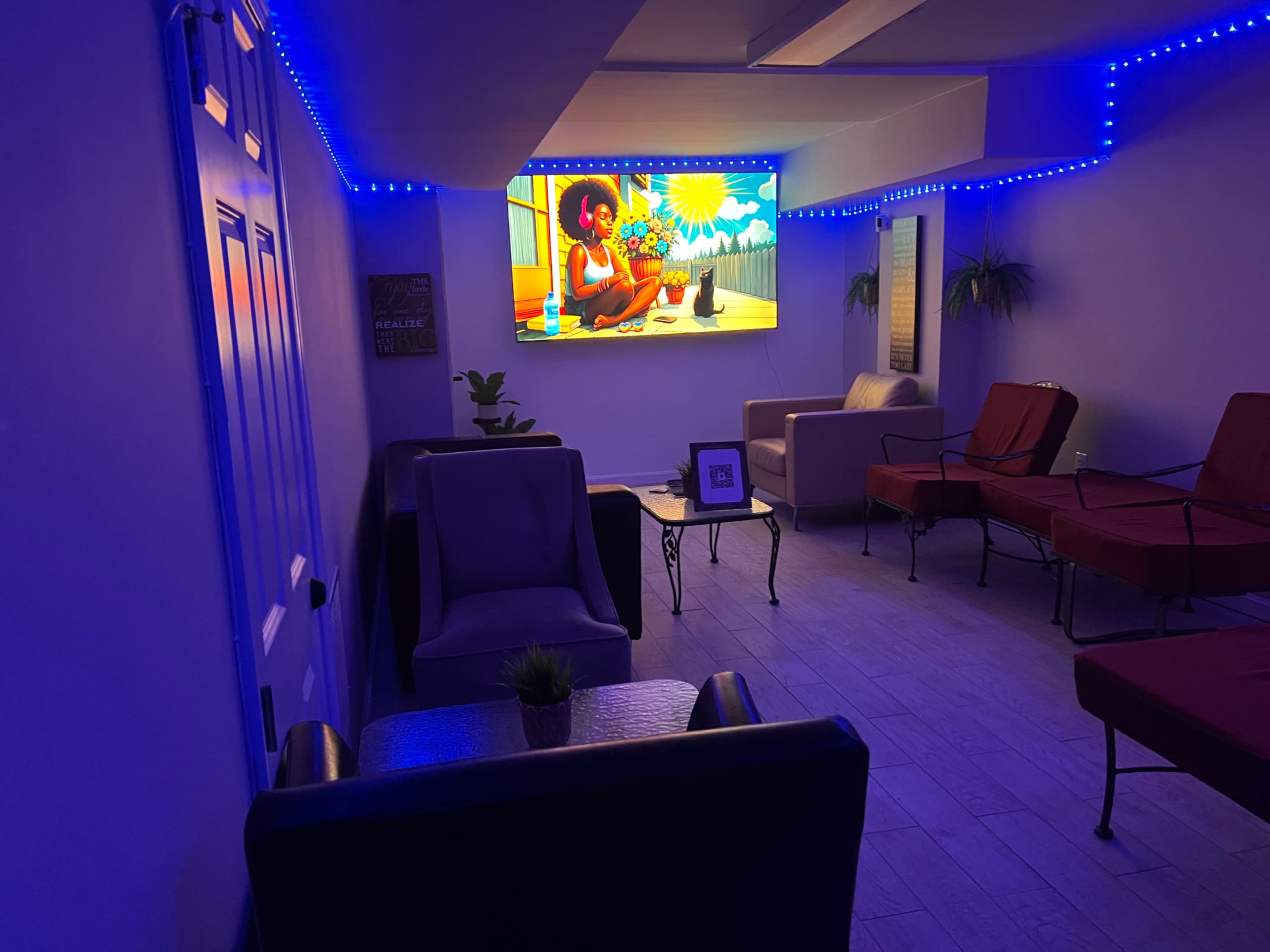 A cozy, modern lounge area features a vibrant digital screen displaying animated artwork, surrounded by comfortable seating and ambient lighting.