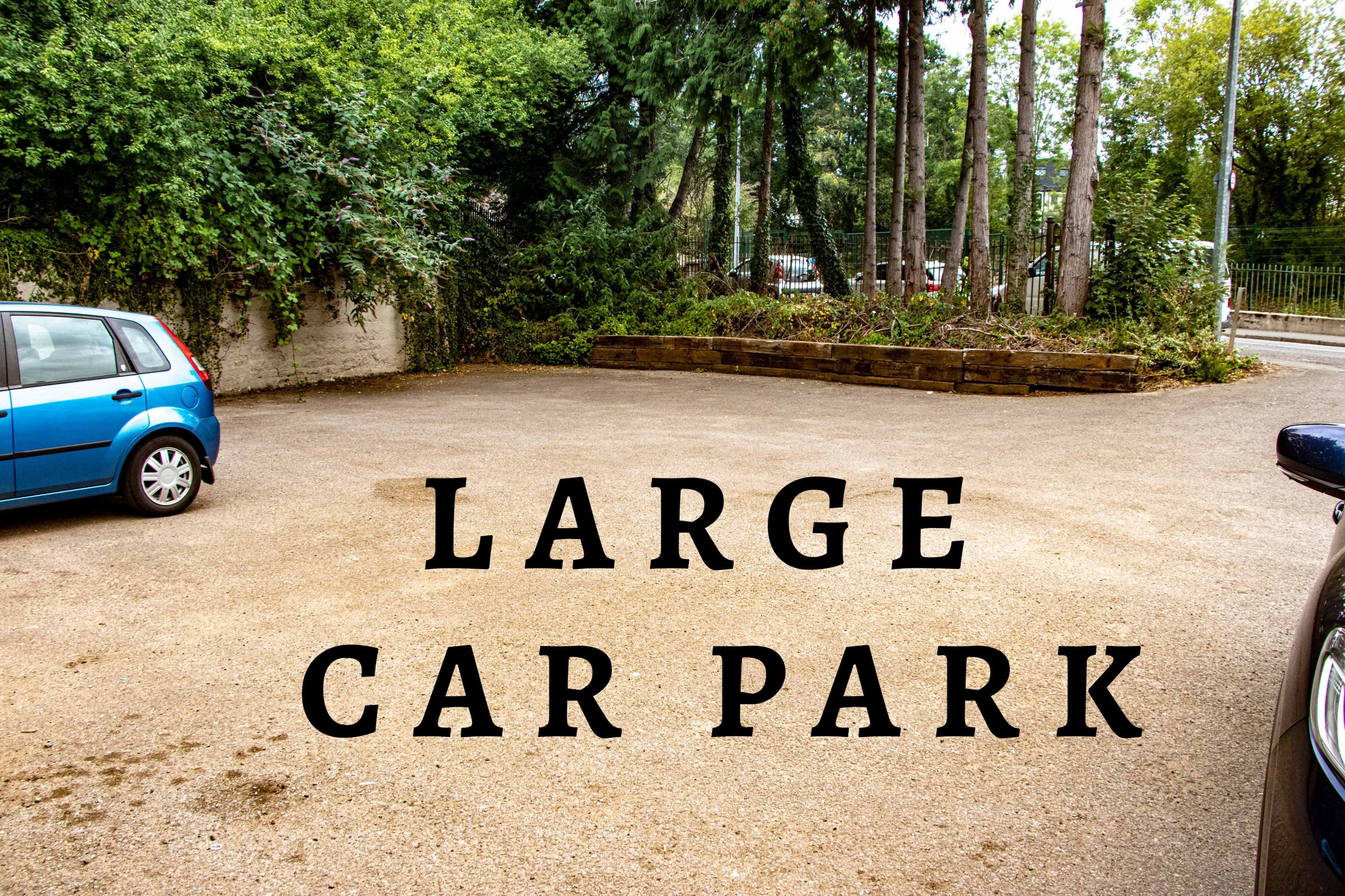A spacious car park surrounded by trees and greenery.