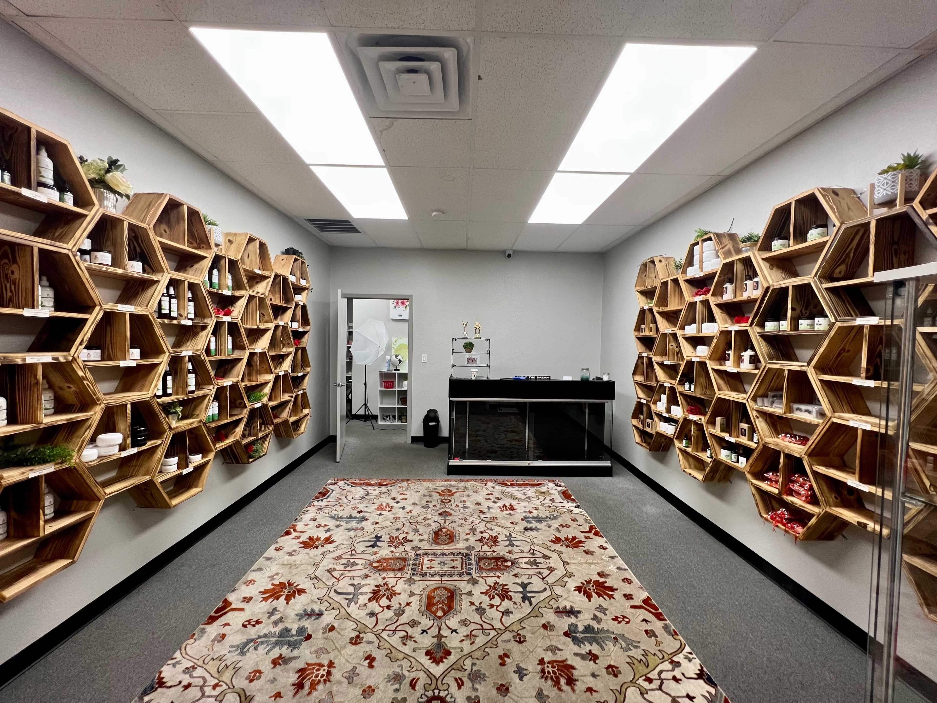 A modern retail space with hexagon-shaped wooden shelves lined with products and a central checkout counter, featuring a patterned rug on the floor.