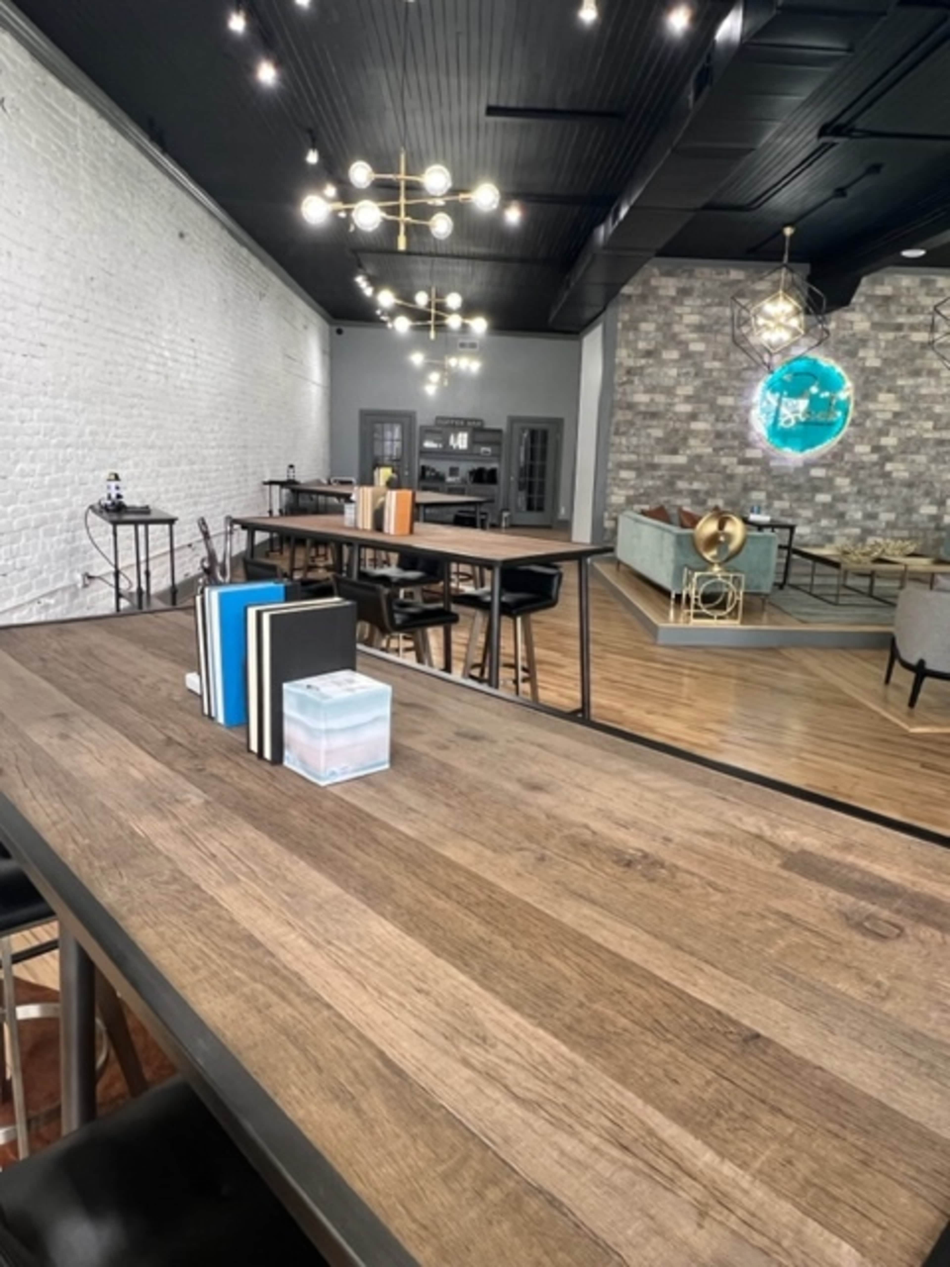 A modern interior space featuring wooden tables, a kitchen area in the background, and various decorative elements.