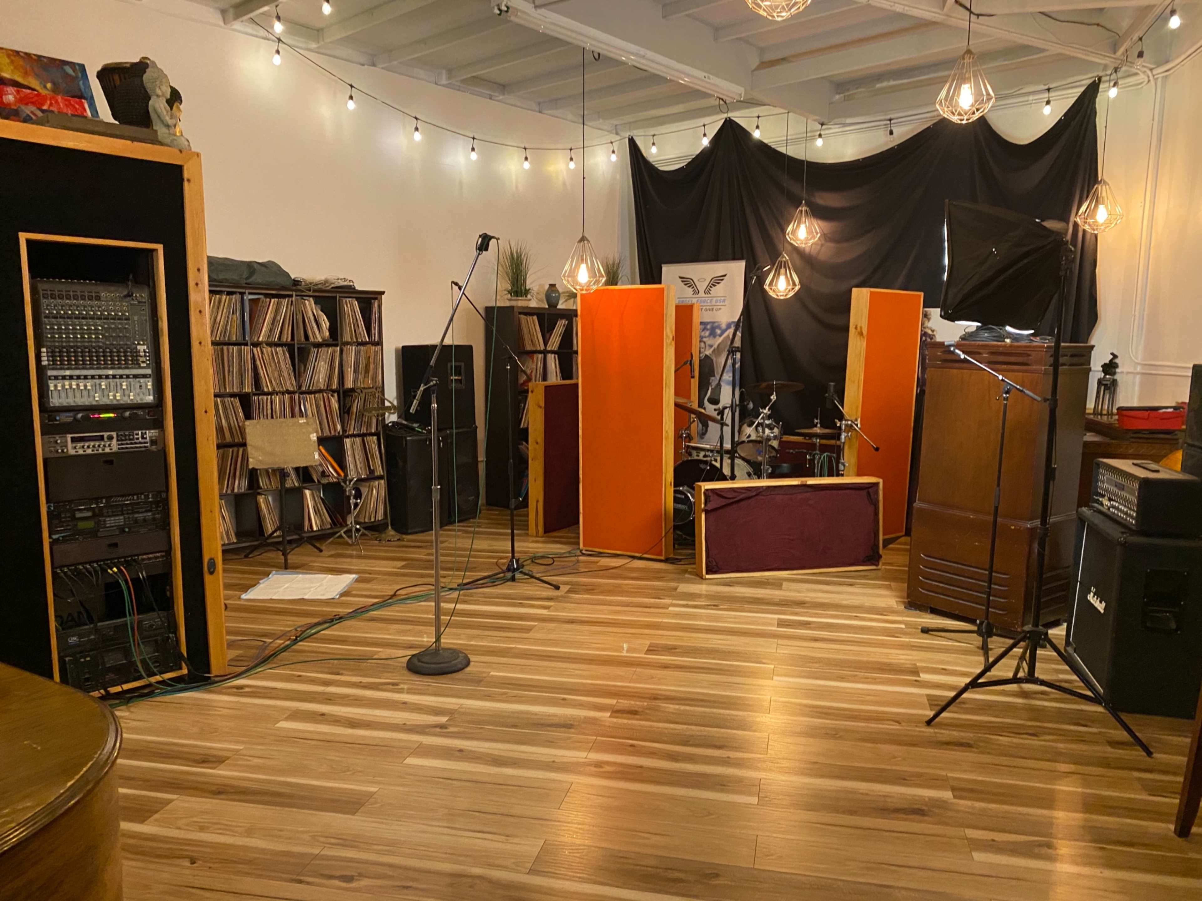 A recording studio with musical equipment, including microphones, amplifiers, and shelves filled with vinyl records.
