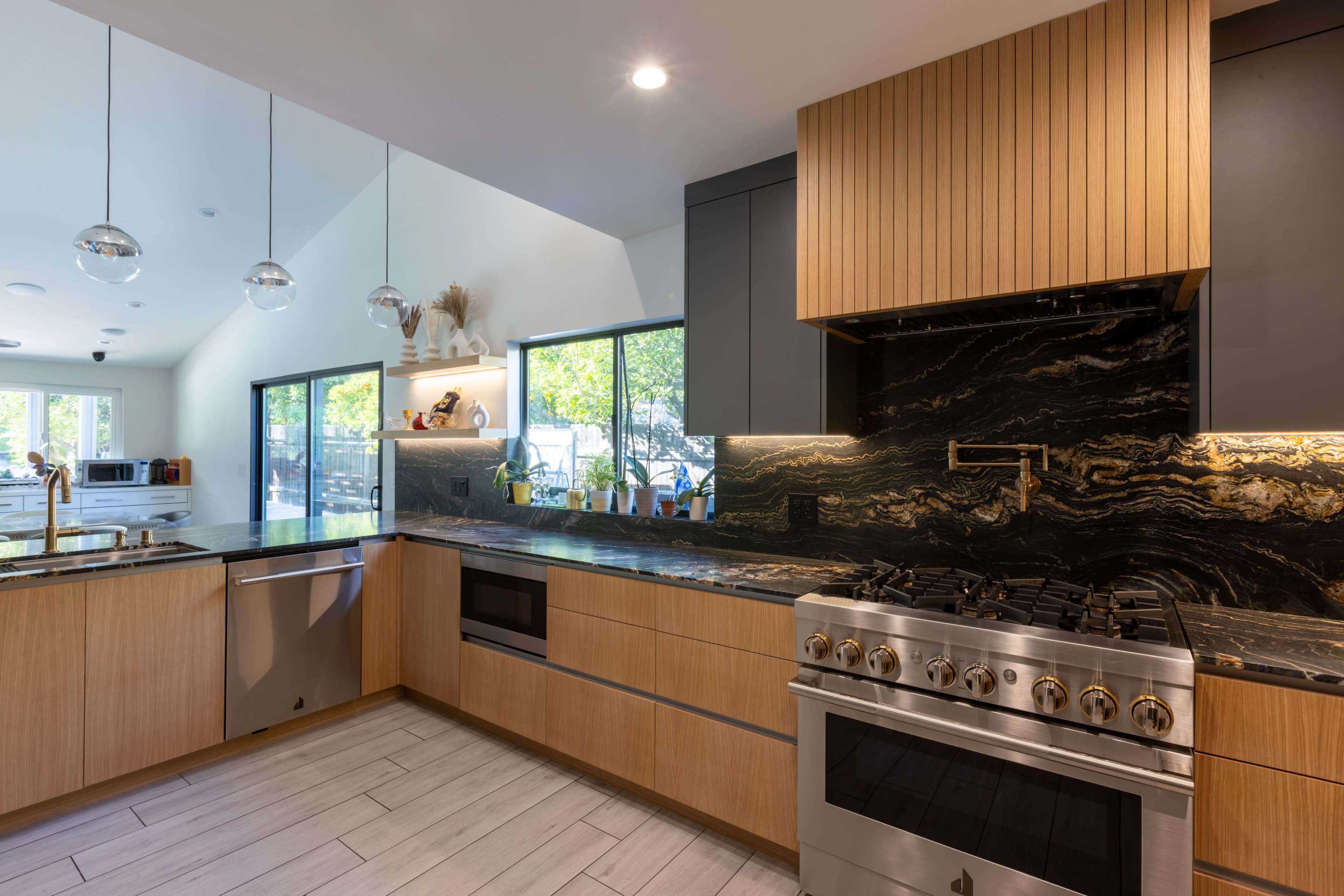 A modern kitchen with wooden cabinetry, a dark stone countertop, and a stainless steel gas range.
