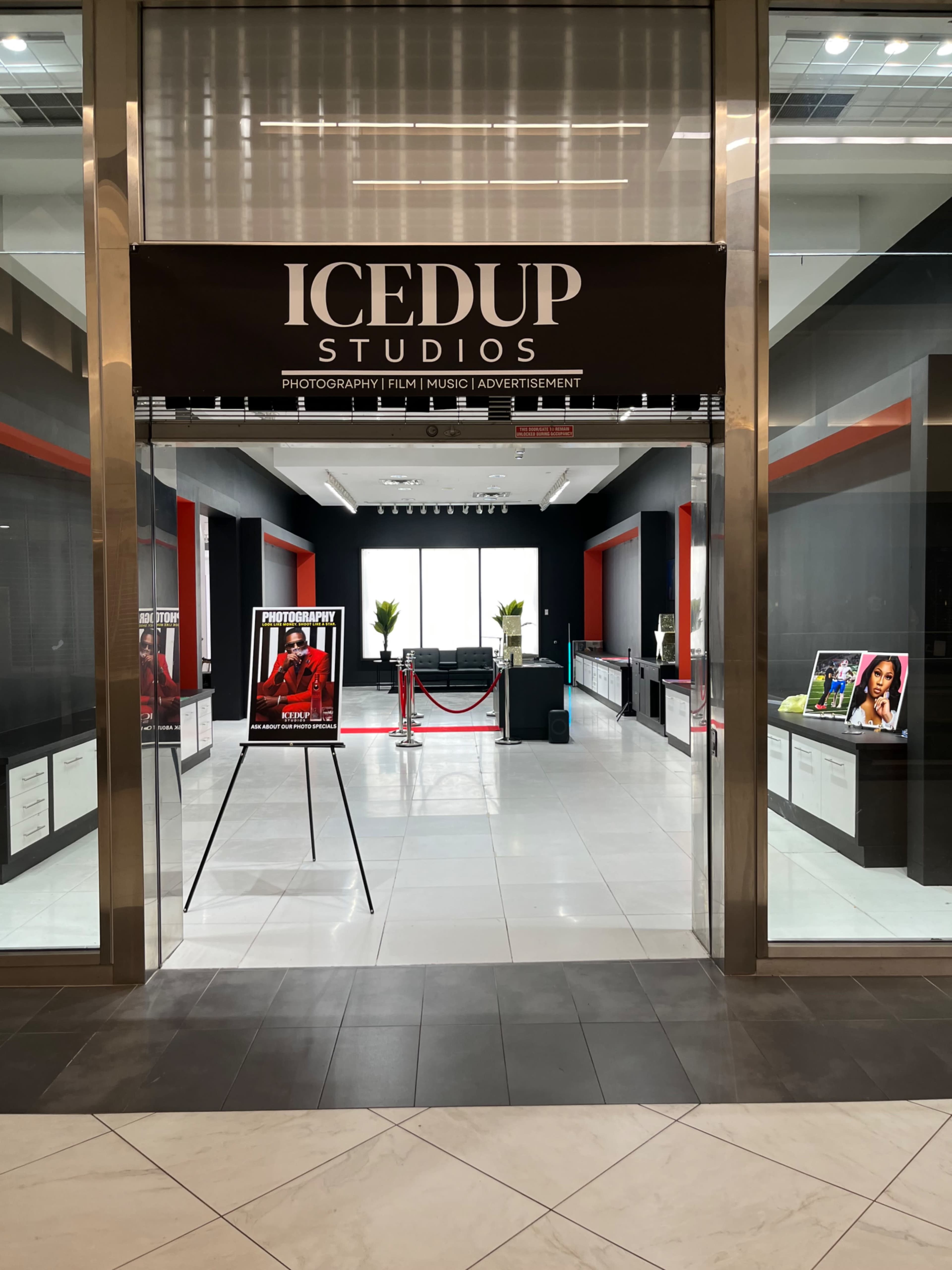 The entrance of IcedUp Studios features a spacious lobby with a modern design, showcasing photography-related displays and decorative plants.