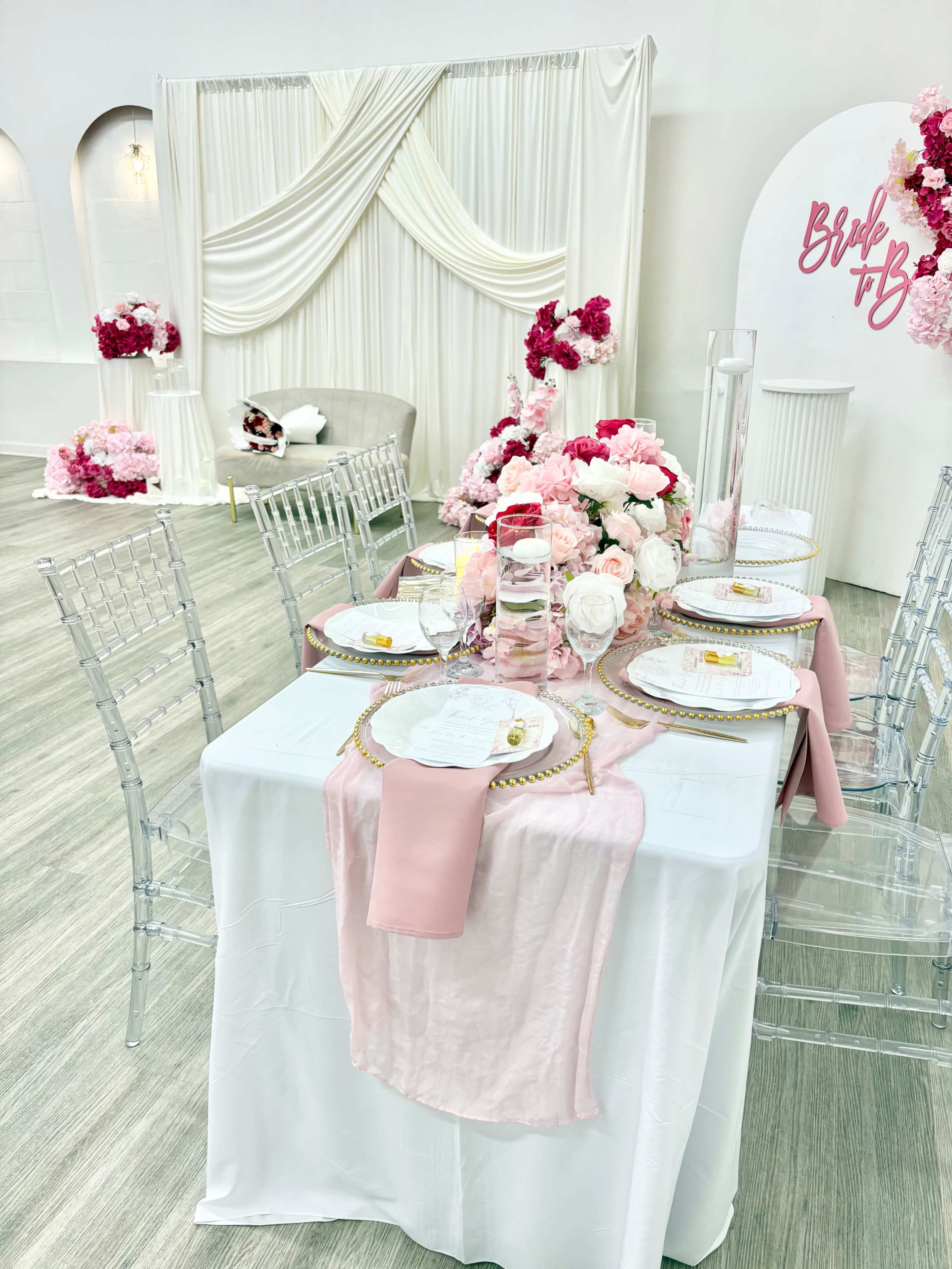 The image shows a elegantly set dining table adorned with pink flowers and decorative elements in a banquet setting.
