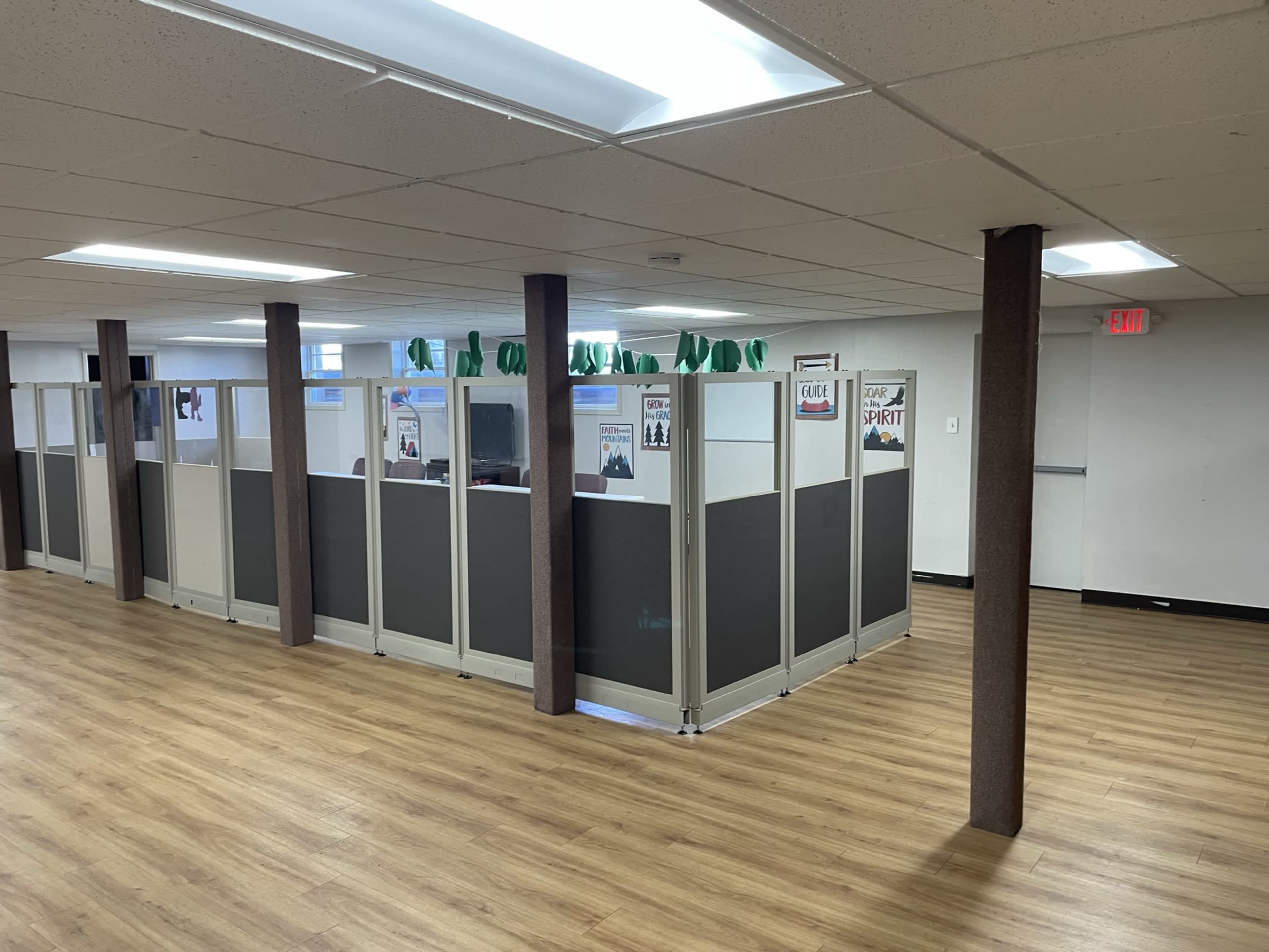 A modern office space featuring cubicles with grey partitions and wooden flooring.