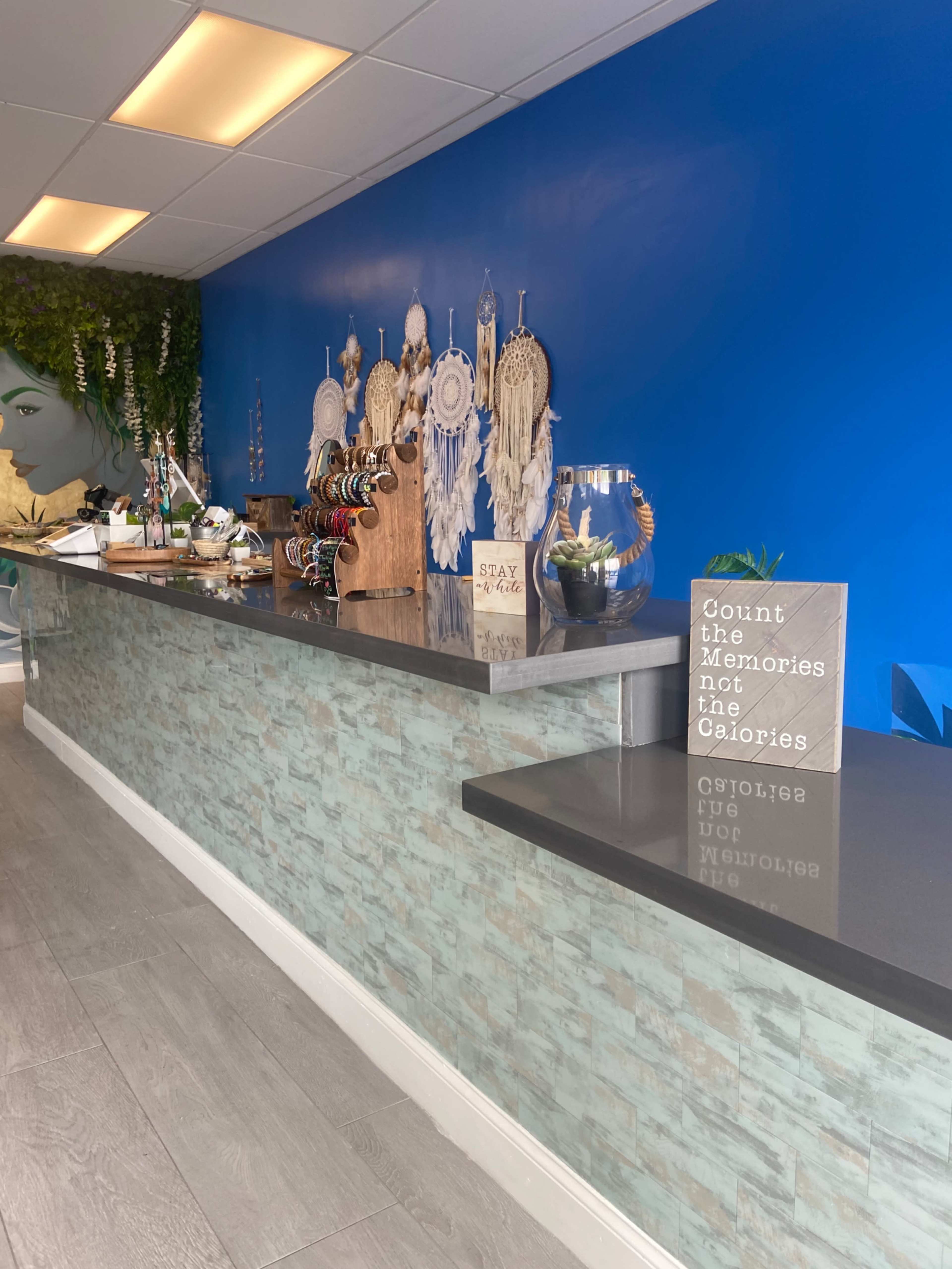 The image shows a boutique interior with a blue wall, decorated with dreamcatchers and jewelry for sale on a counter, along with a motivational sign.