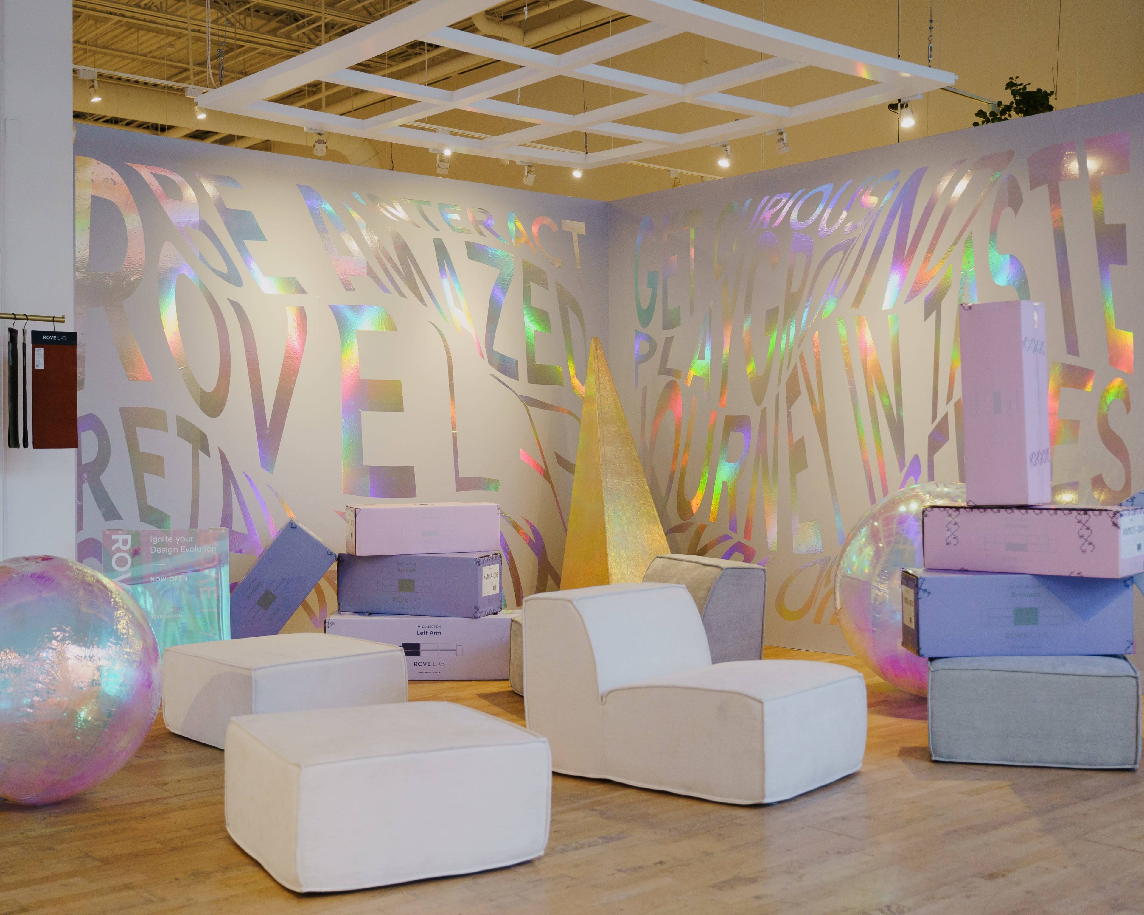 The image shows a modern, art-filled space with colorful, reflective walls and various geometric seating arrangements along with transparent spherical shapes.