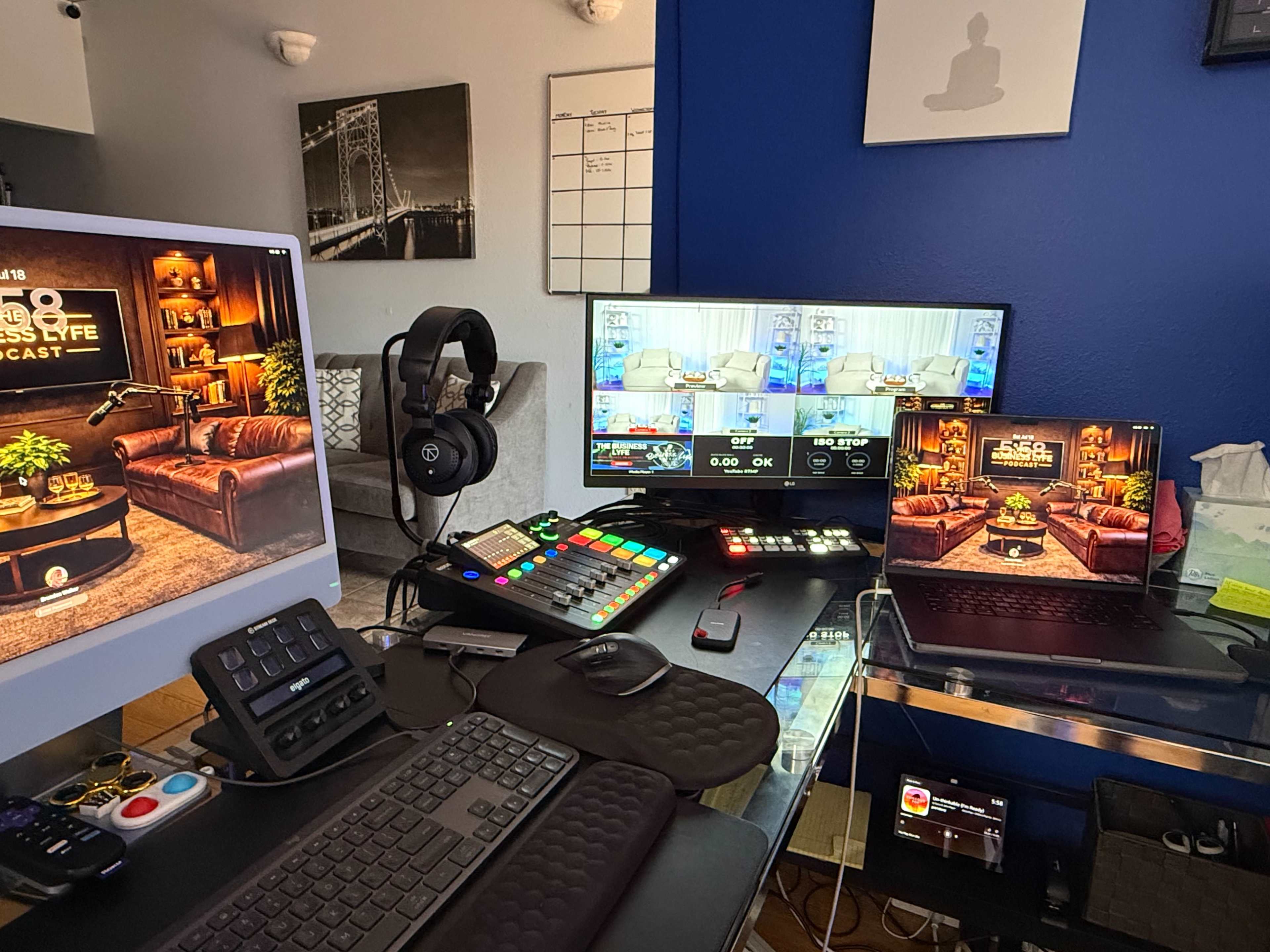 A workspace setup featuring multiple monitors, a gaming headset, and a control panel surrounded by various electronic devices.