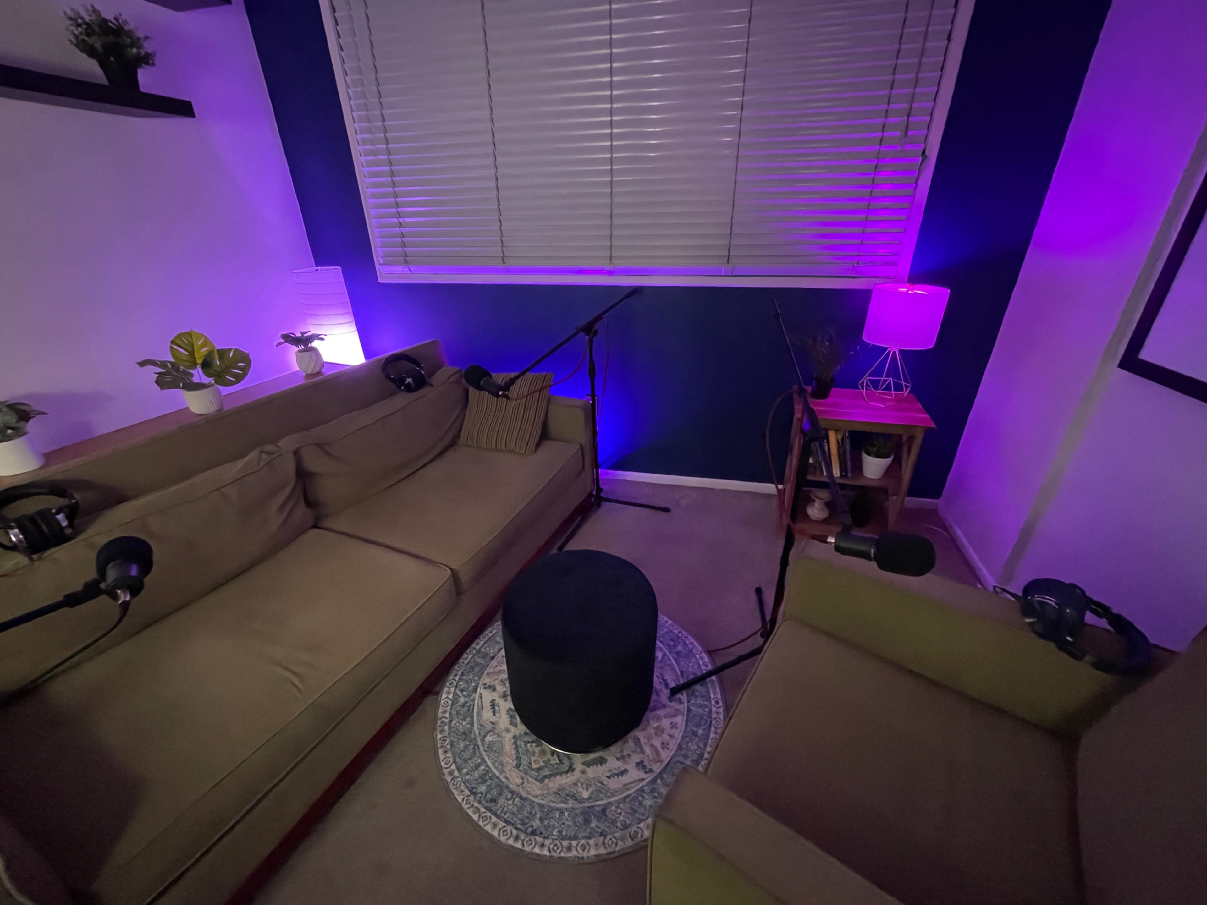 A small recording studio is set up with two couches, microphones, and ambient lighting.