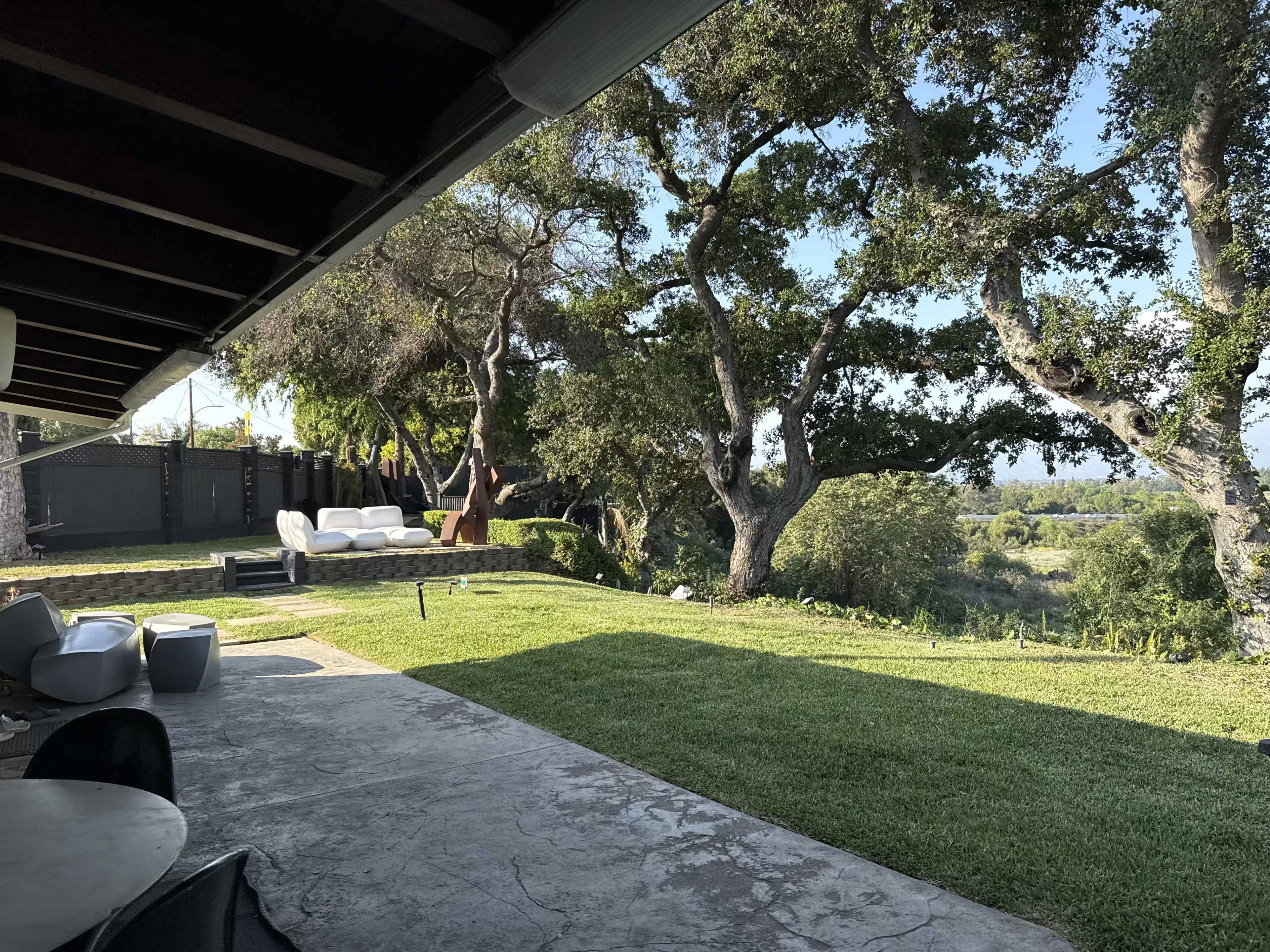 A covered patio overlooks a lawn with trees and a distant landscape.
