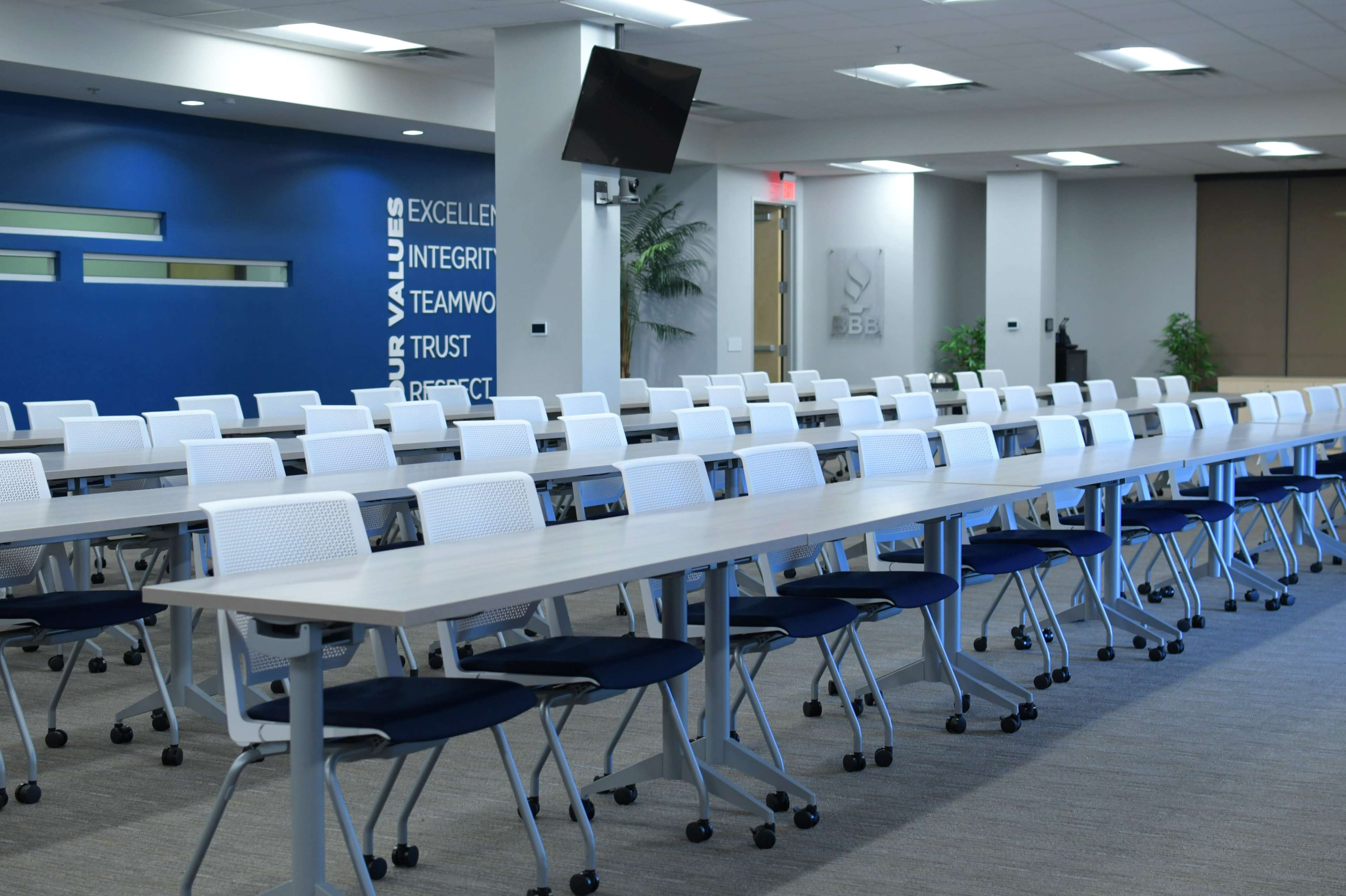 A spacious conference room set up with multiple rows of tables and chairs arranged for a meeting.