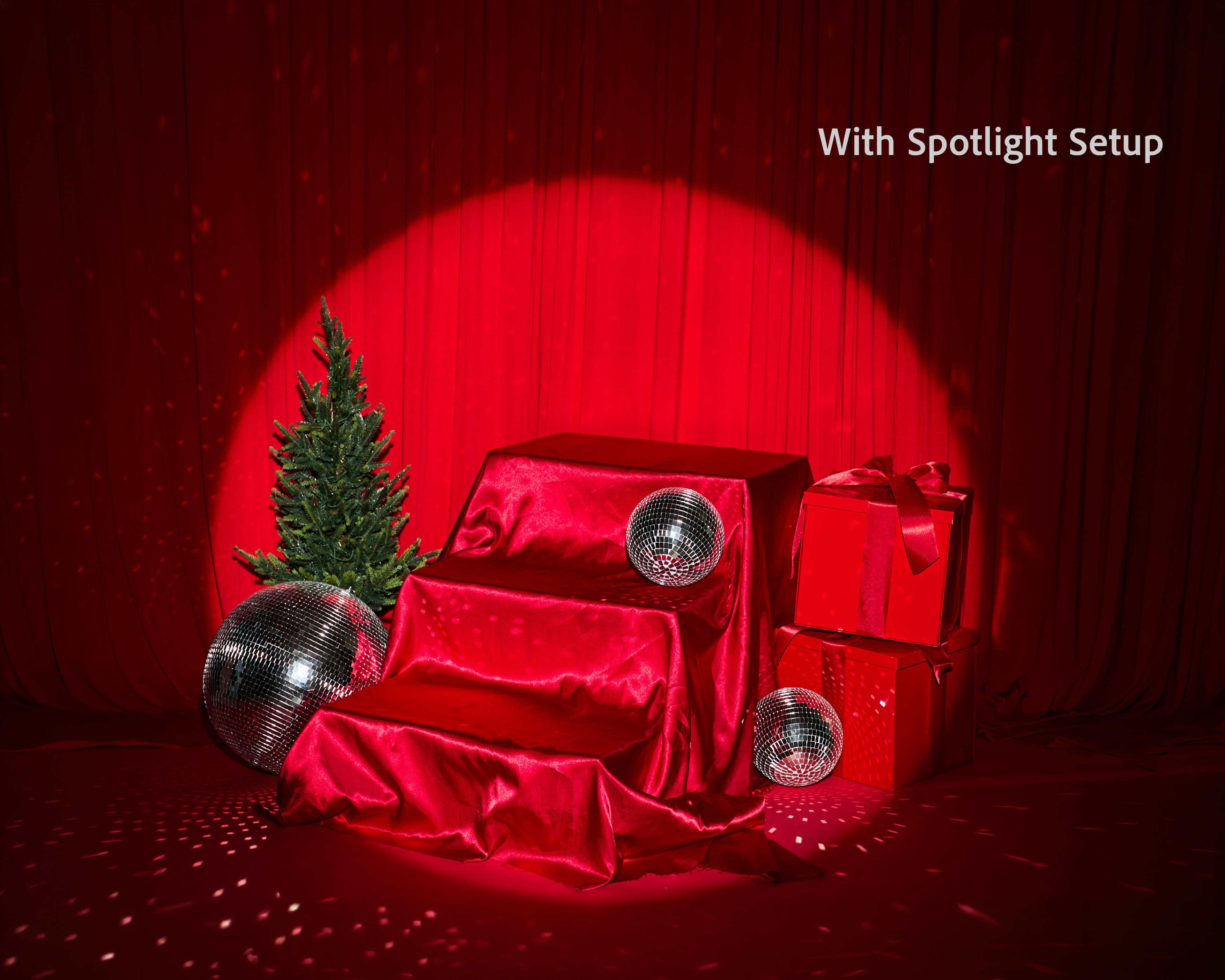 The scene features a red background with draped fabric, two gift boxes, a small Christmas tree, and three reflective disco balls illuminated by a spotlight.