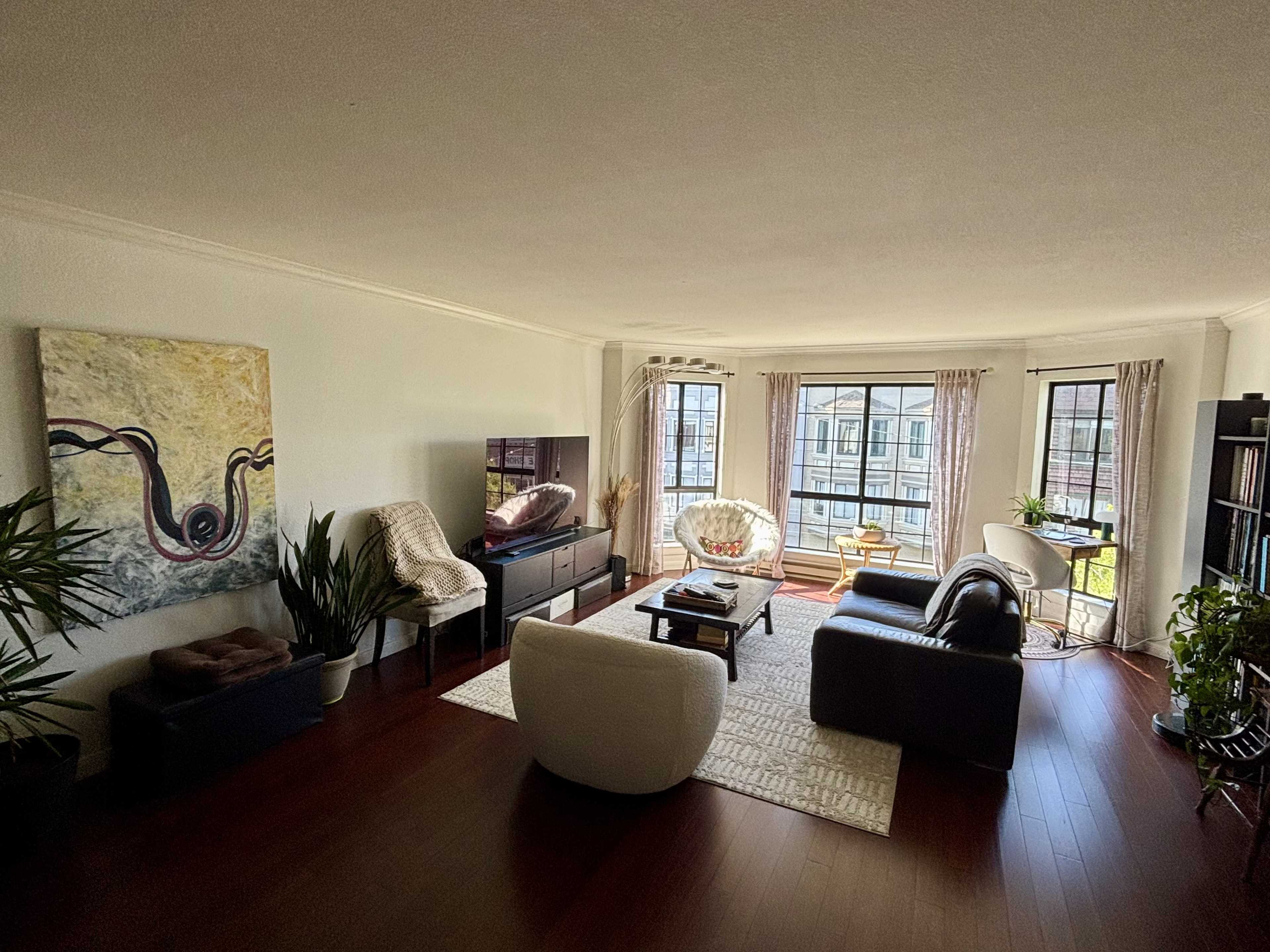 A modern living room features a mix of seating options, a coffee table, and large windows allowing natural light to fill the space.