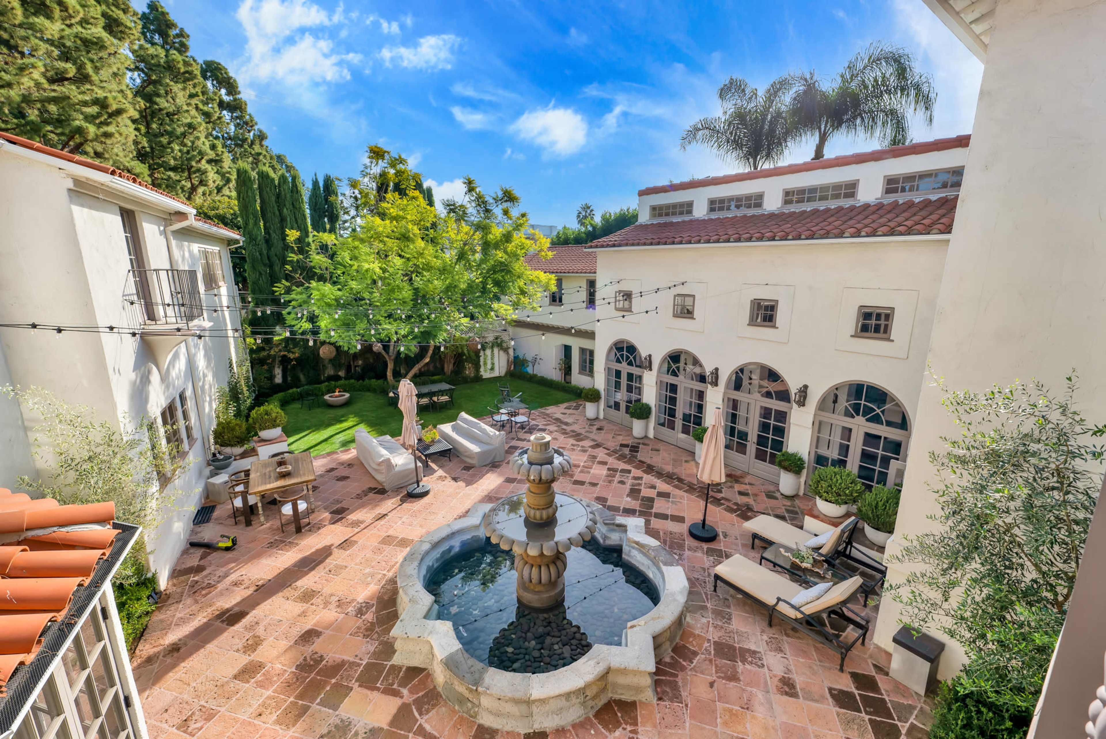 A courtyard with a central fountain surrounded by seating areas and lush greenery.