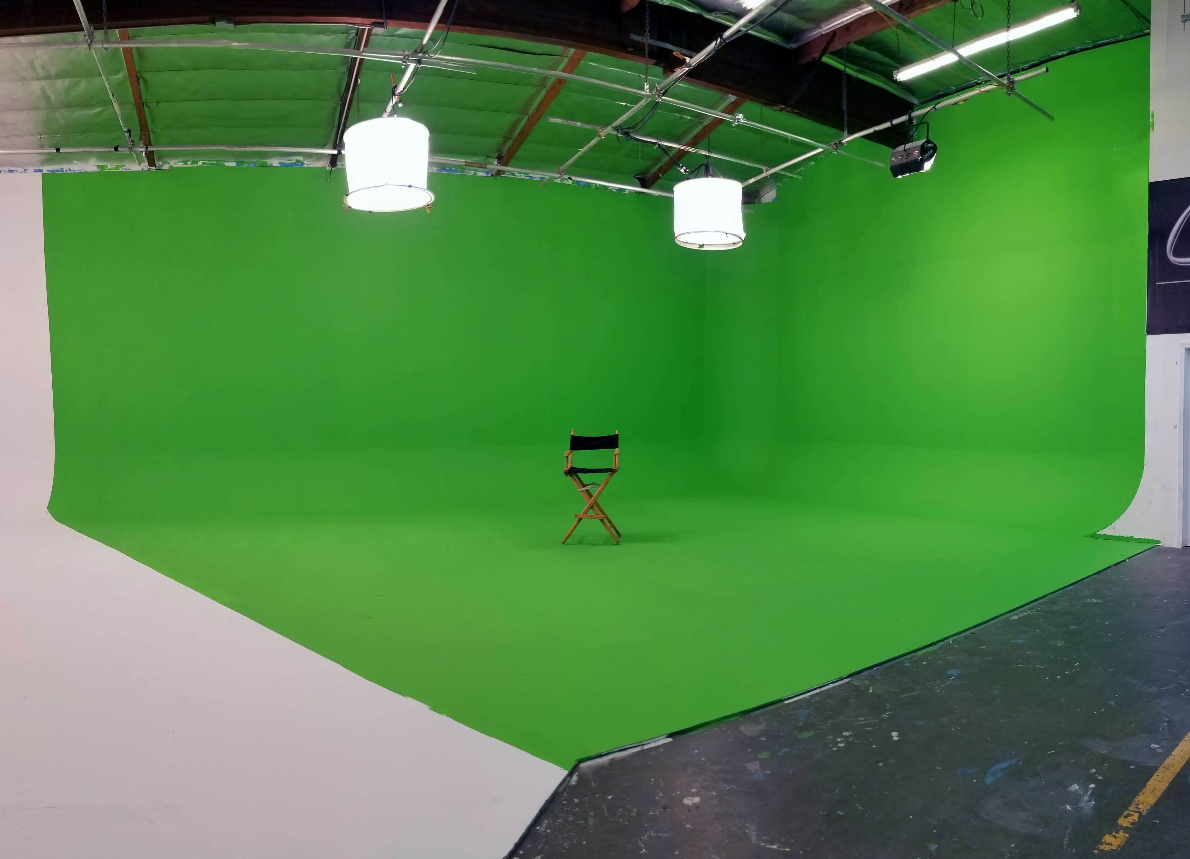 A large green screen studio with a lone director's chair positioned in the center.