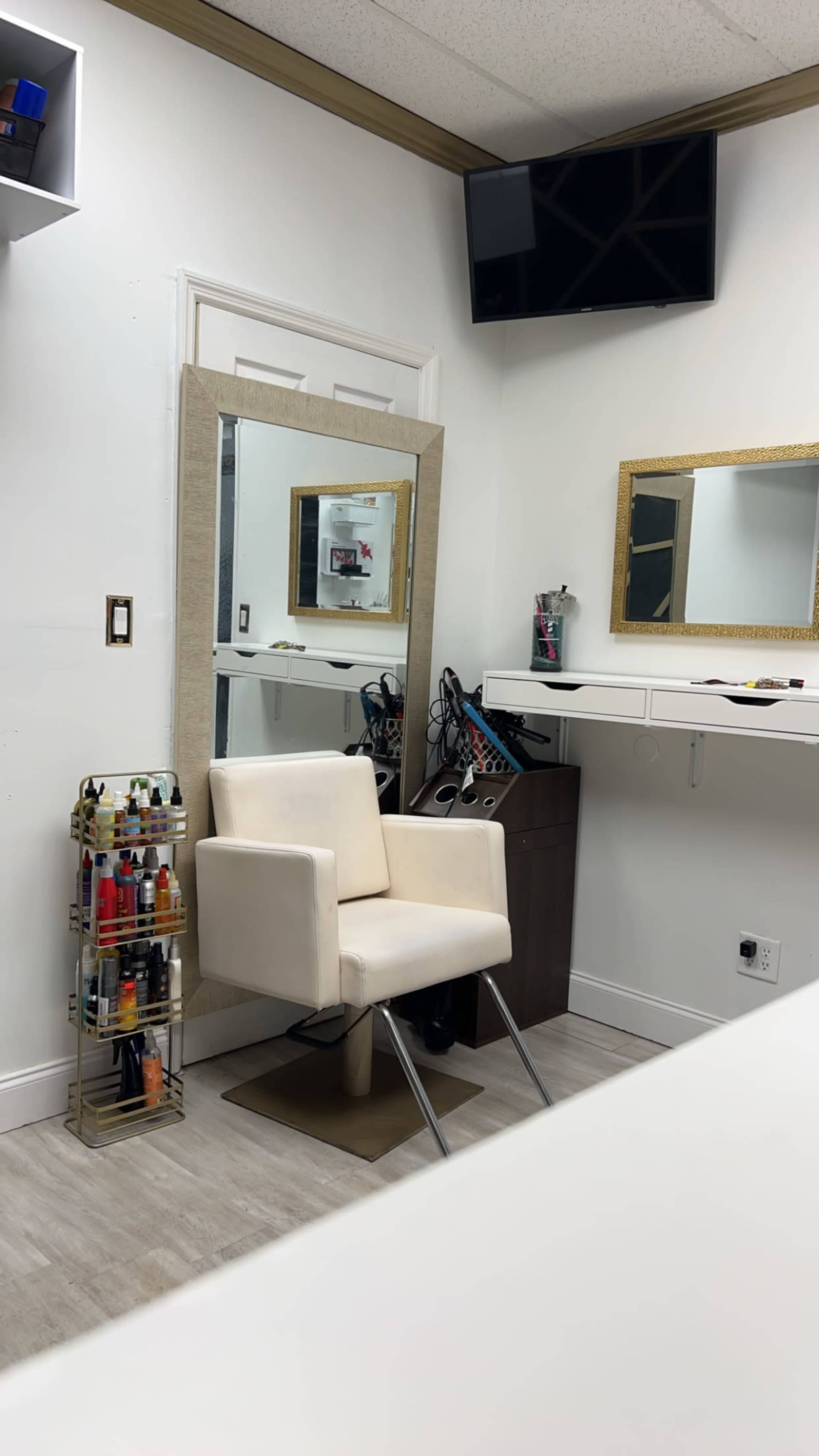 A small salon with a stylist chair, a mirror, and a shelf displaying nail polish bottles.