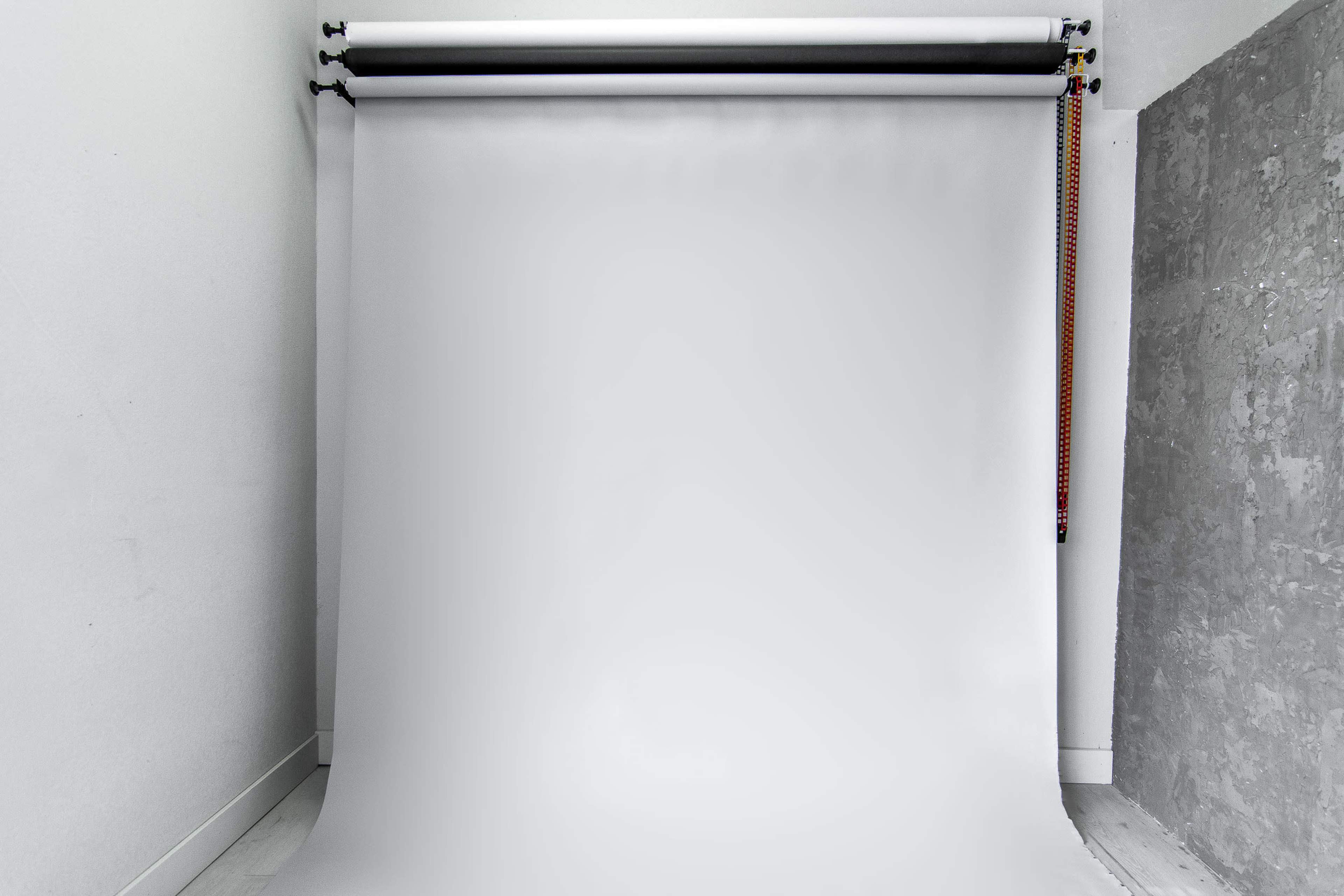 A blank photography backdrop in a studio setting, with a smooth, white surface and a gray side wall.