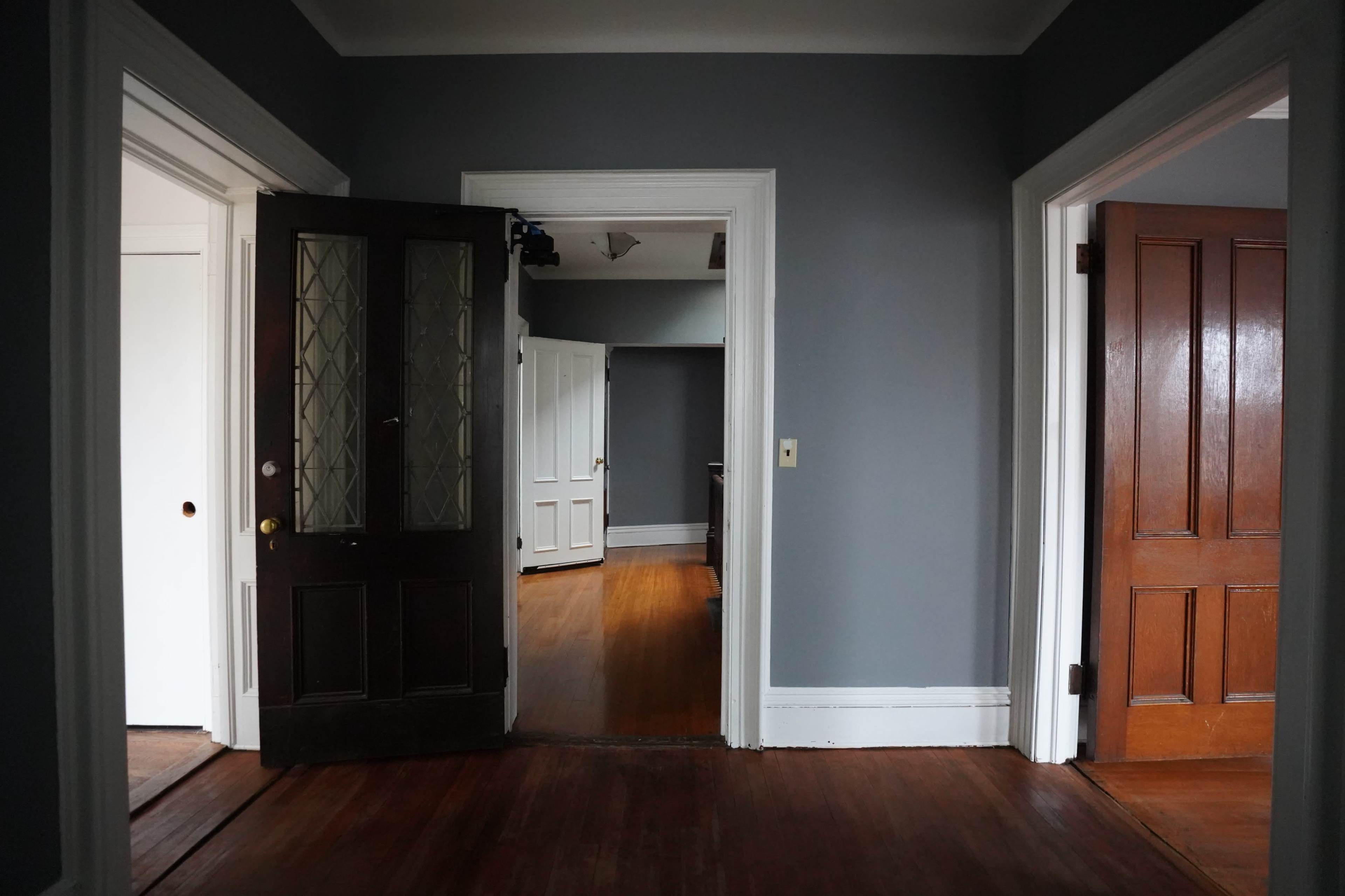 A hallway in a house with doorways leading to different rooms and hardwood floors.