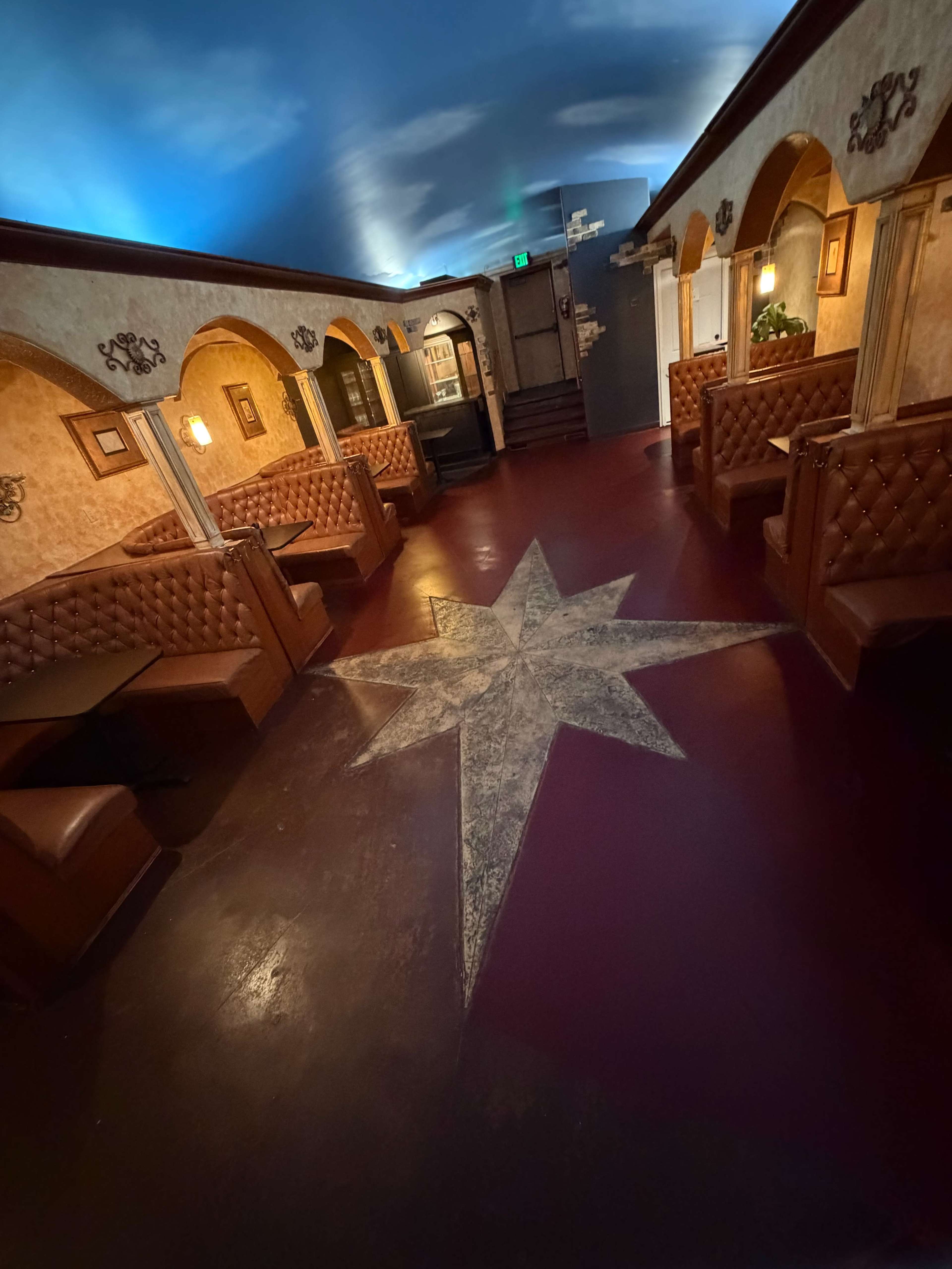 The image shows an interior of a restaurant or bar featuring brown leather booths along the walls and a star-patterned design on the floor.