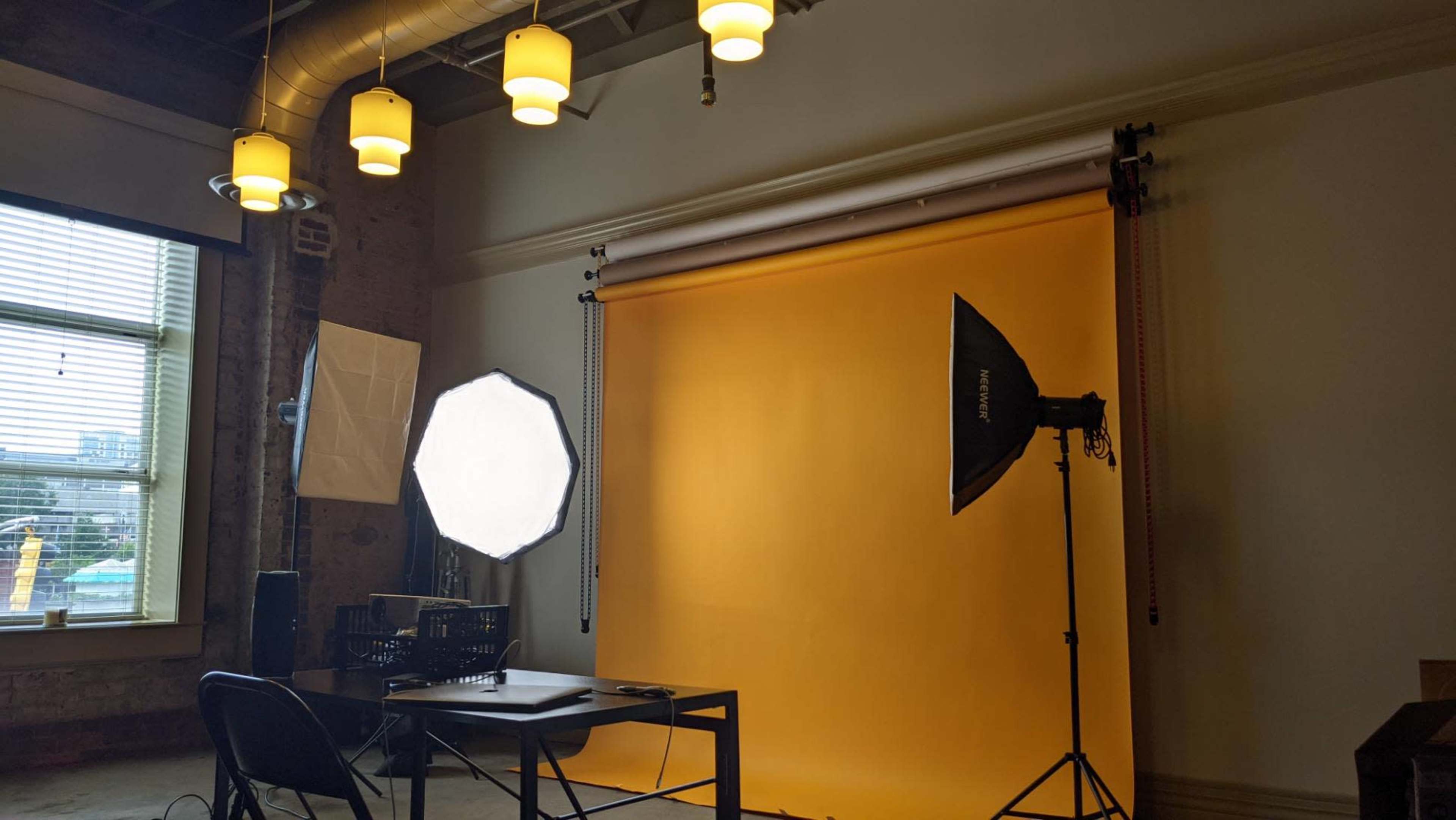 A photography studio setup with a yellow backdrop, softbox lights, and a table in front of the backdrop.