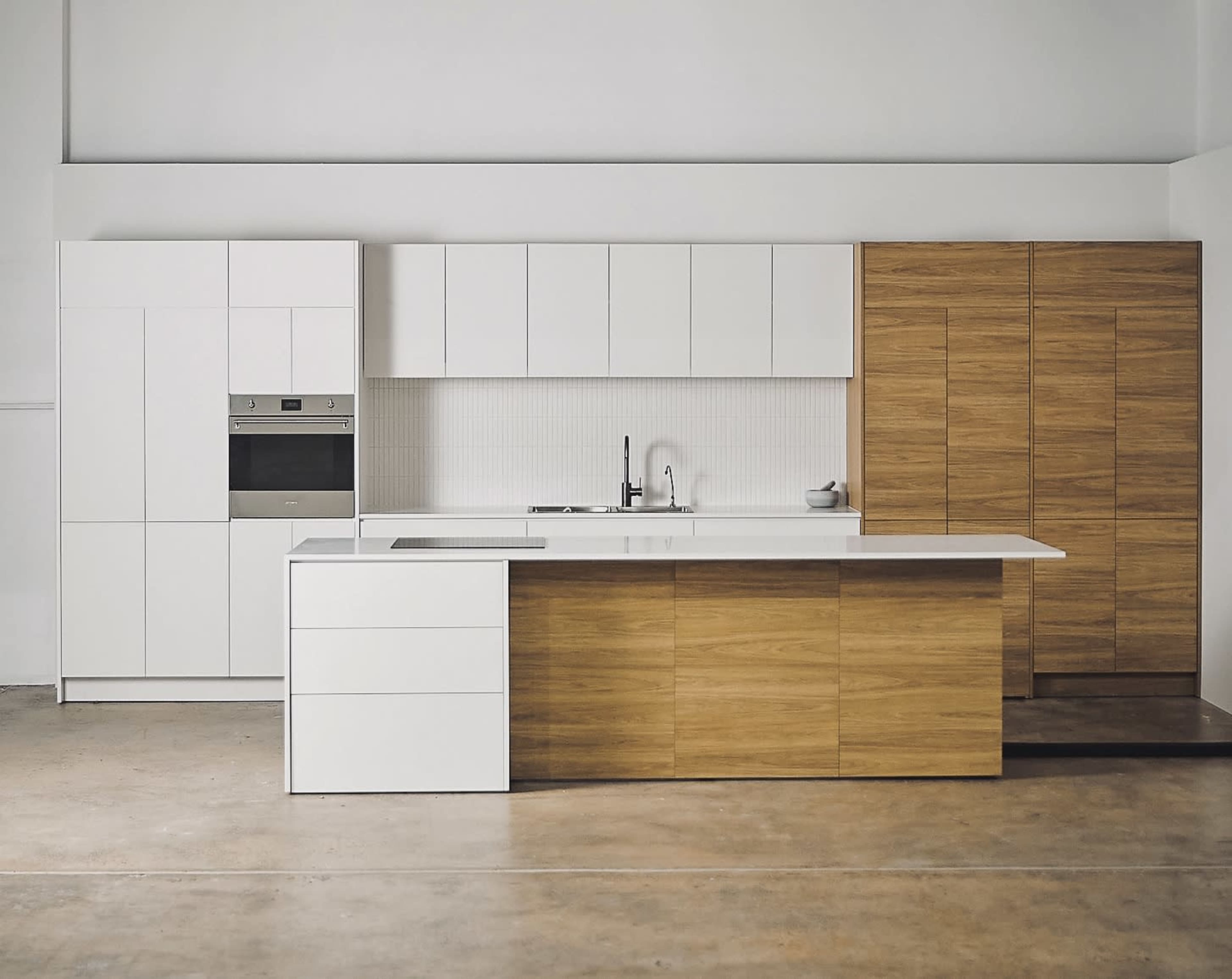 A modern kitchen featuring white cabinets and a wooden island with smooth surfaces and minimalistic design.