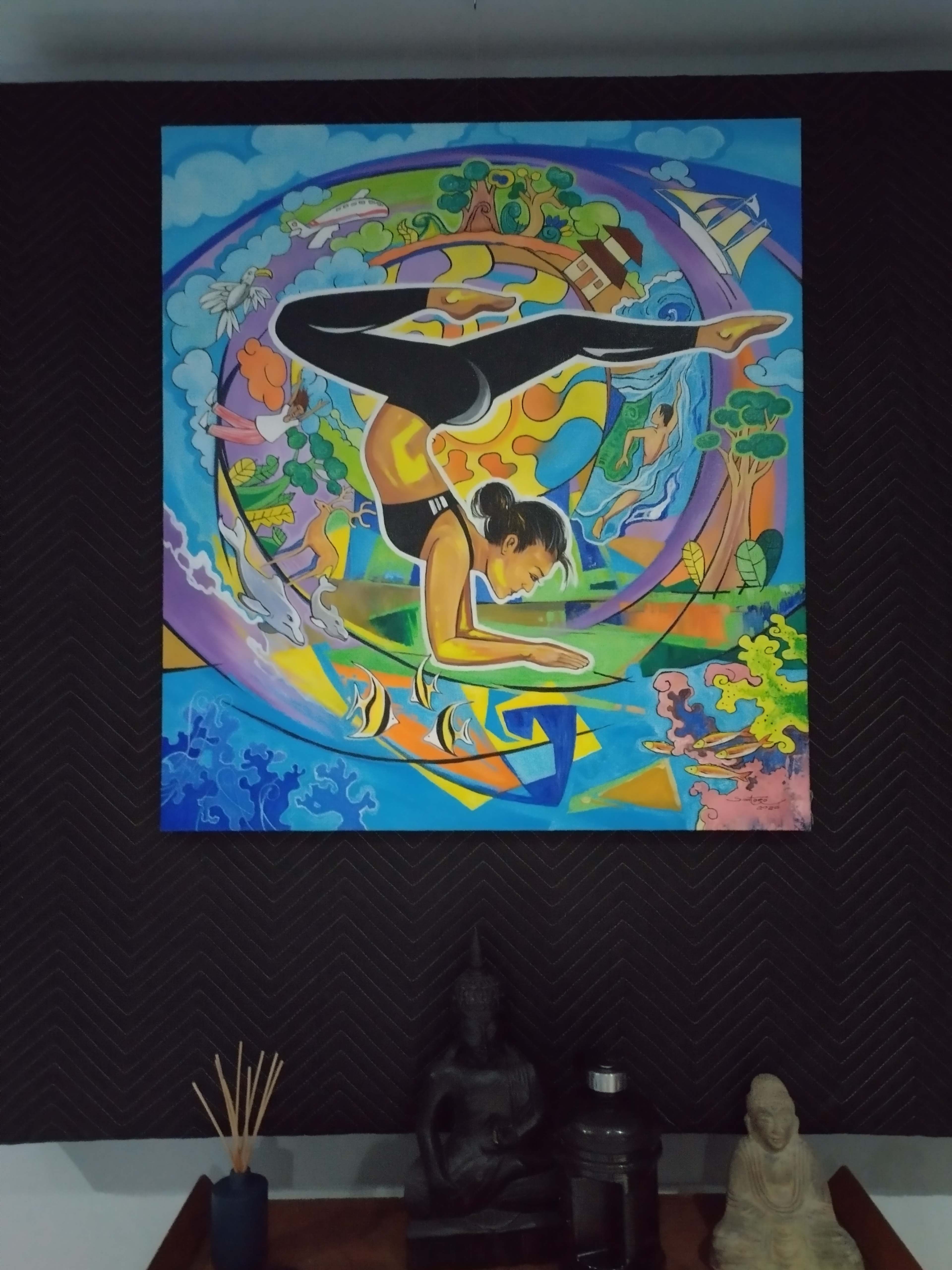 A colorful mural of a woman performing a yoga pose surrounded by vibrant nature and abstract elements, hanging above decorative statues on a wooden table.