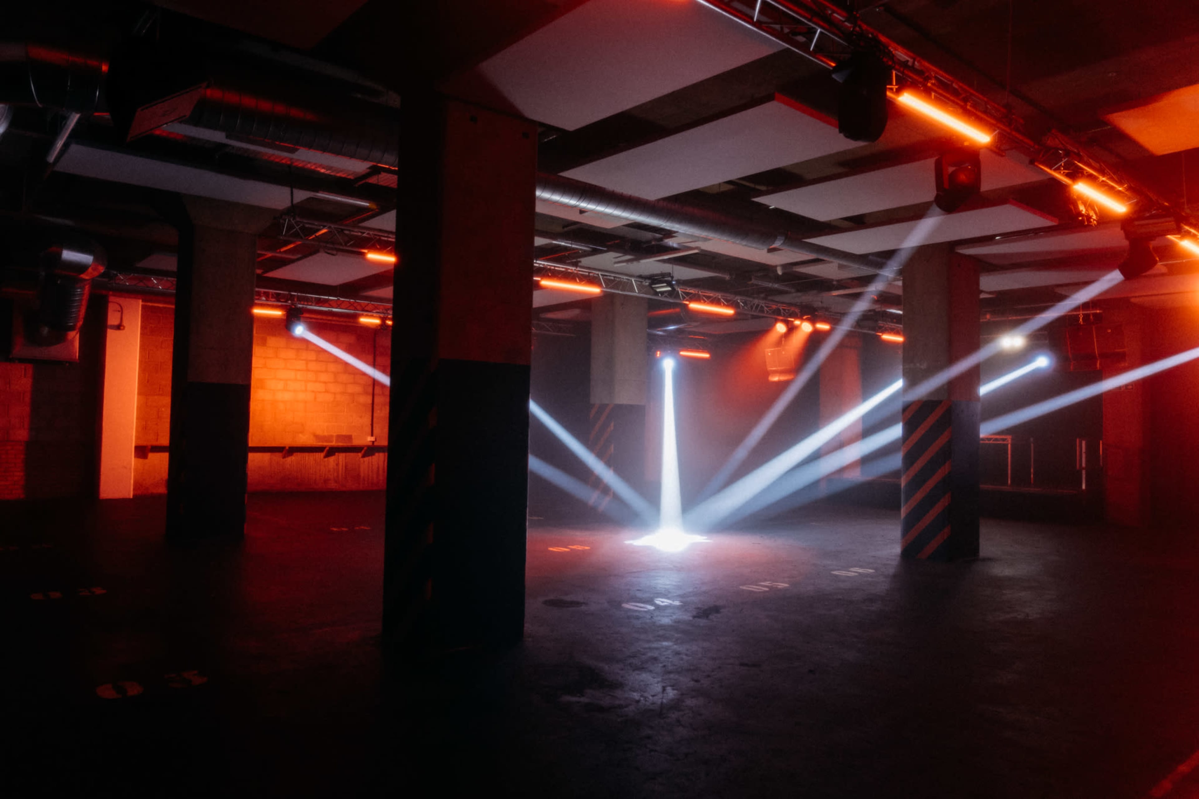 An industrial-style interior space with beams of light cutting through a dark environment, creating a dramatic atmosphere.
