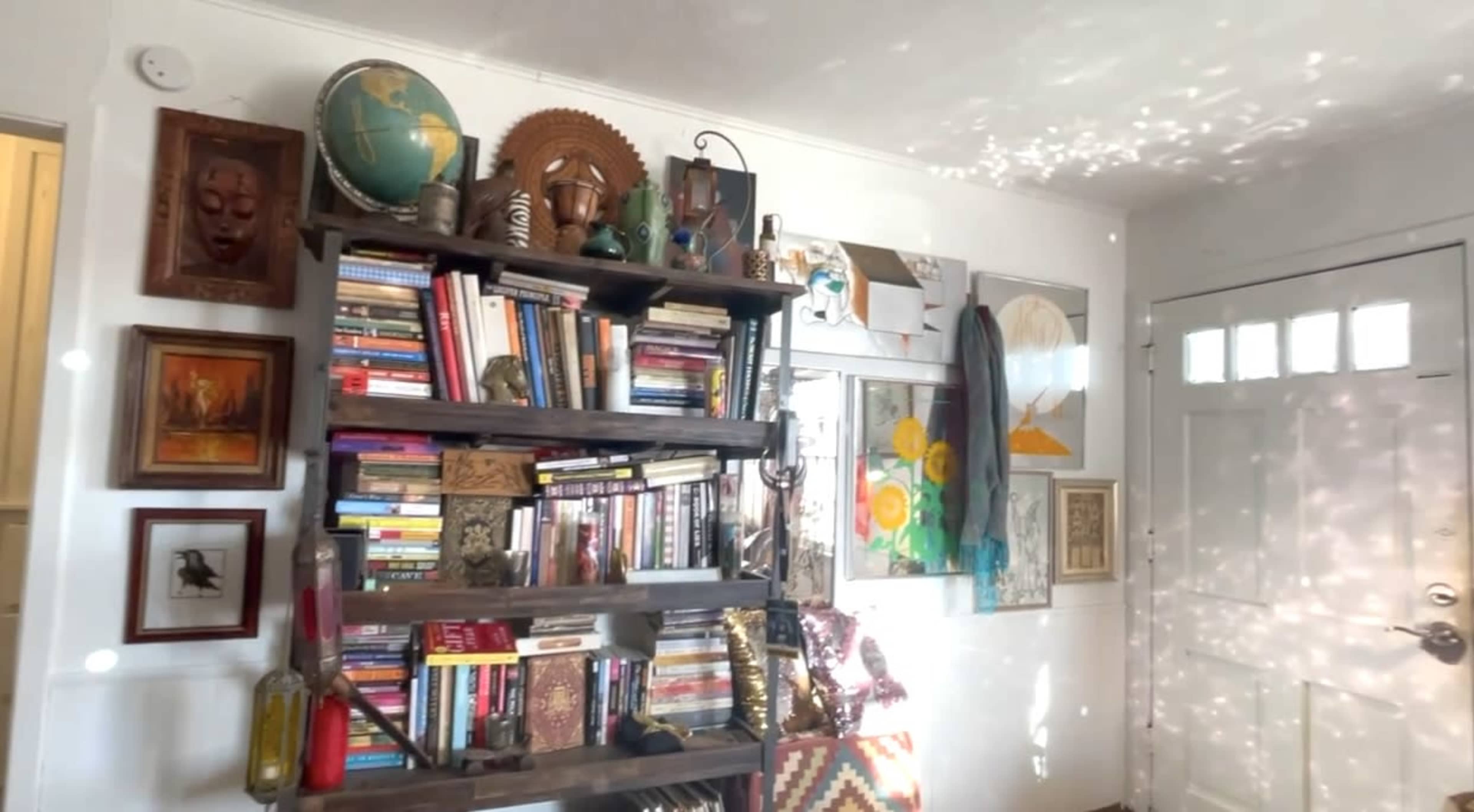 A wooden bookshelf filled with various books and decorative items is positioned against a wall near a door.